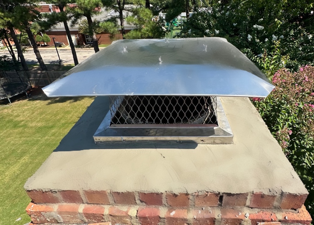 Newly installed stainless steel chimney cap on top of restored brick chimney