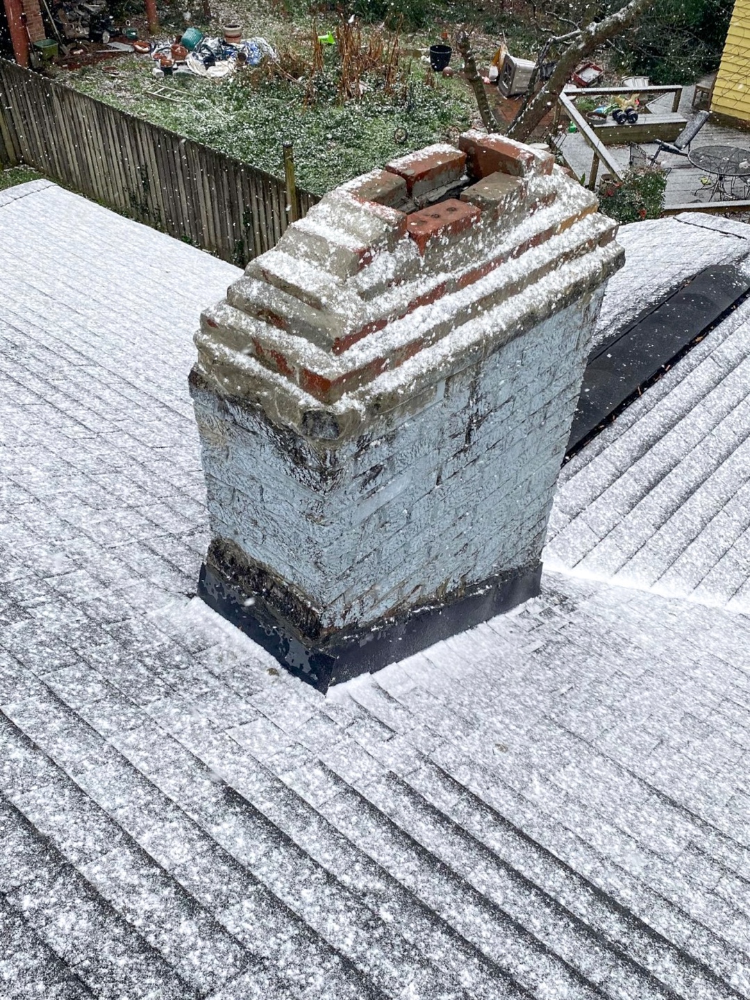 Deteriorating chimney on a roof with visible wear and tear