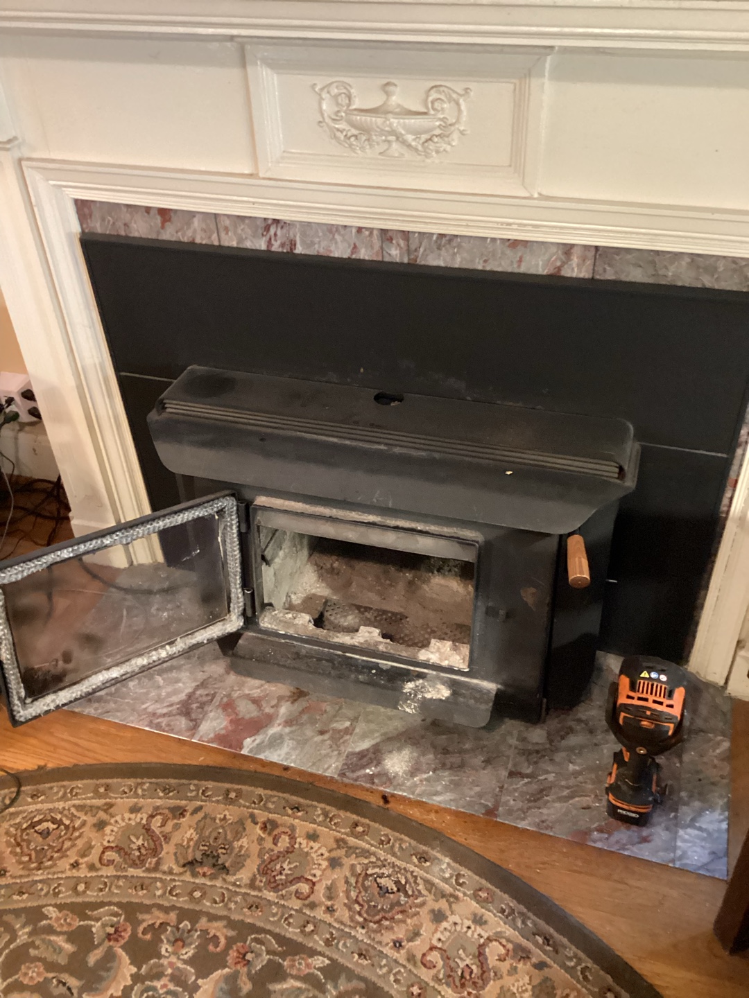 A black wood stove revealing ash and debris inside