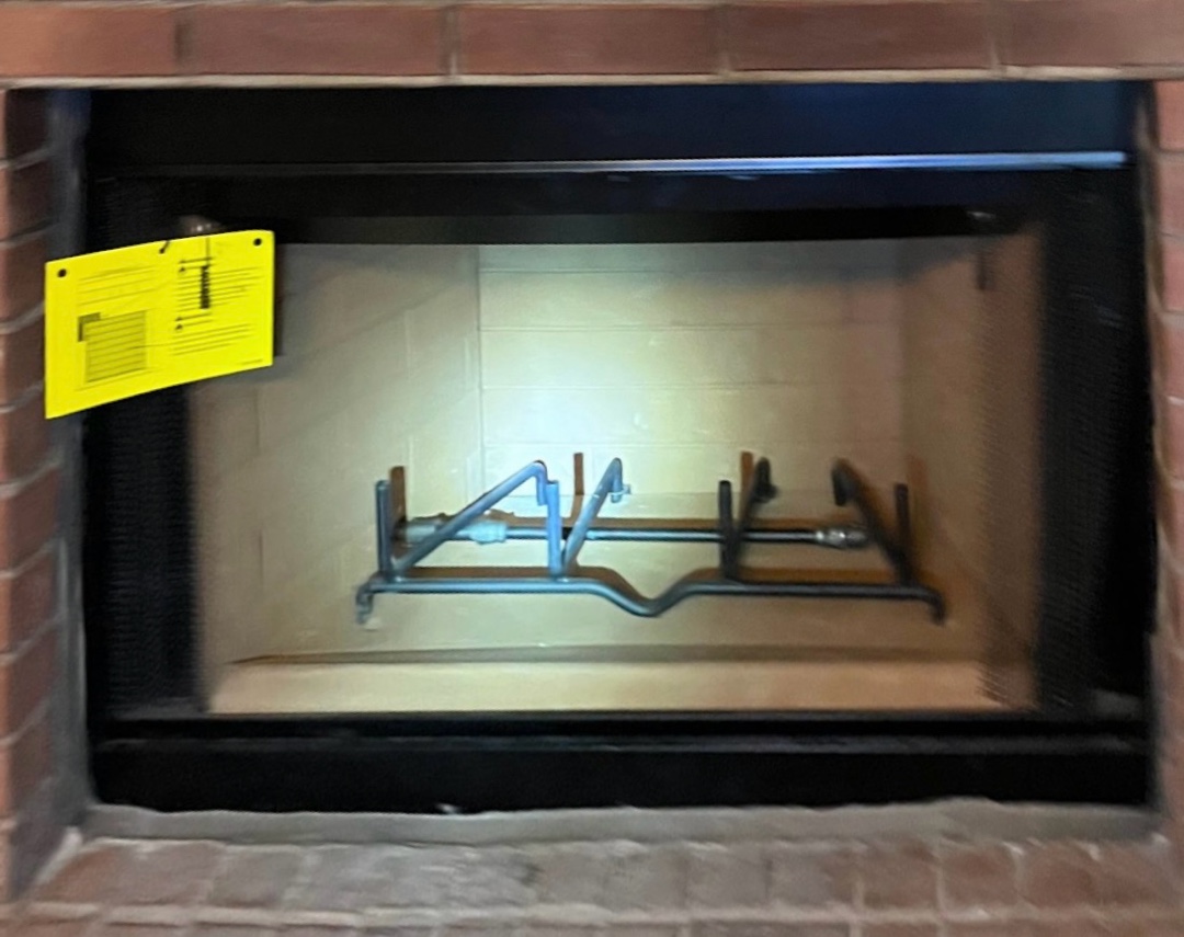 A modern firebox installed within a brick fireplace