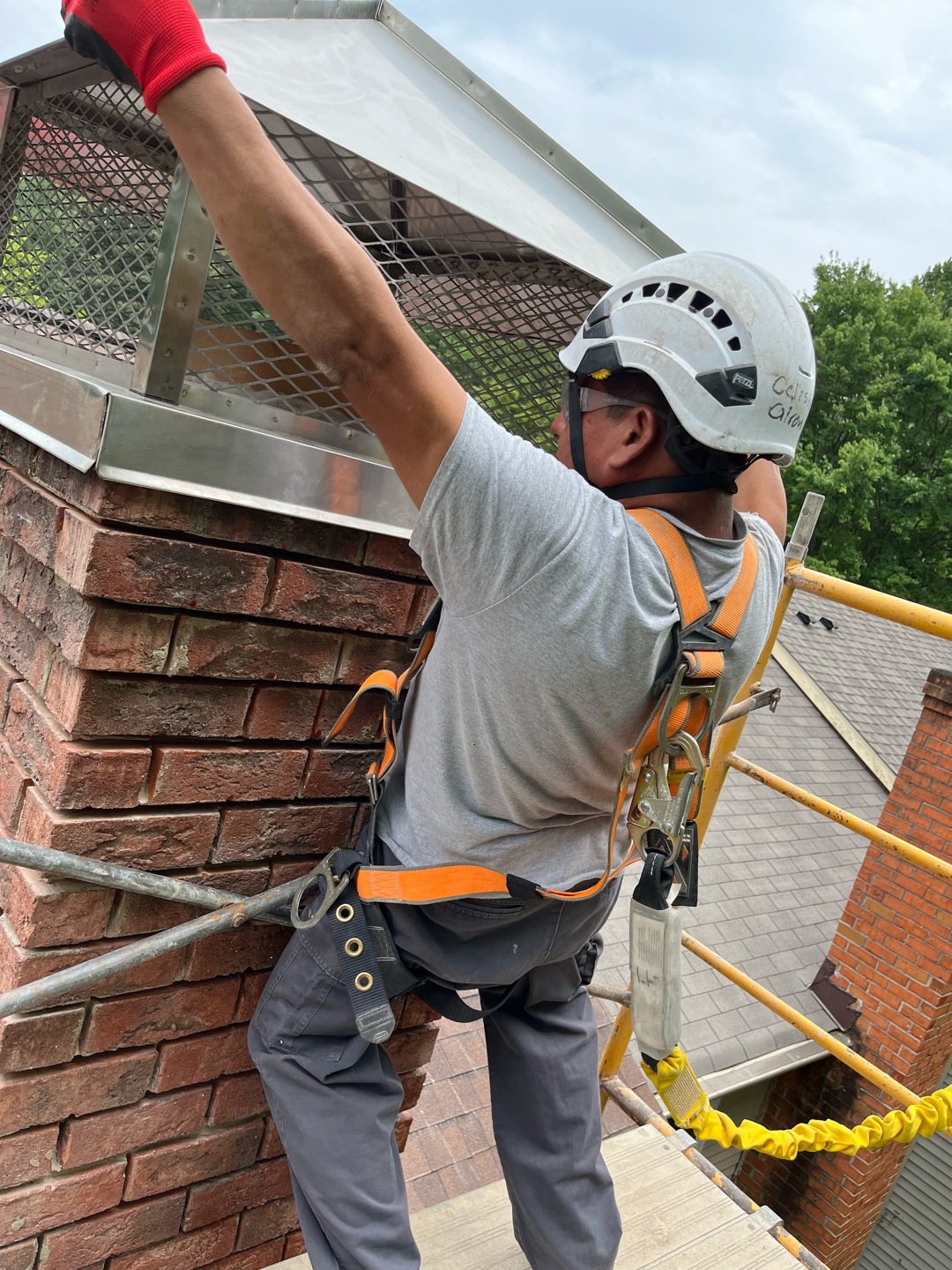 Worker securing metal cap on brick chimney