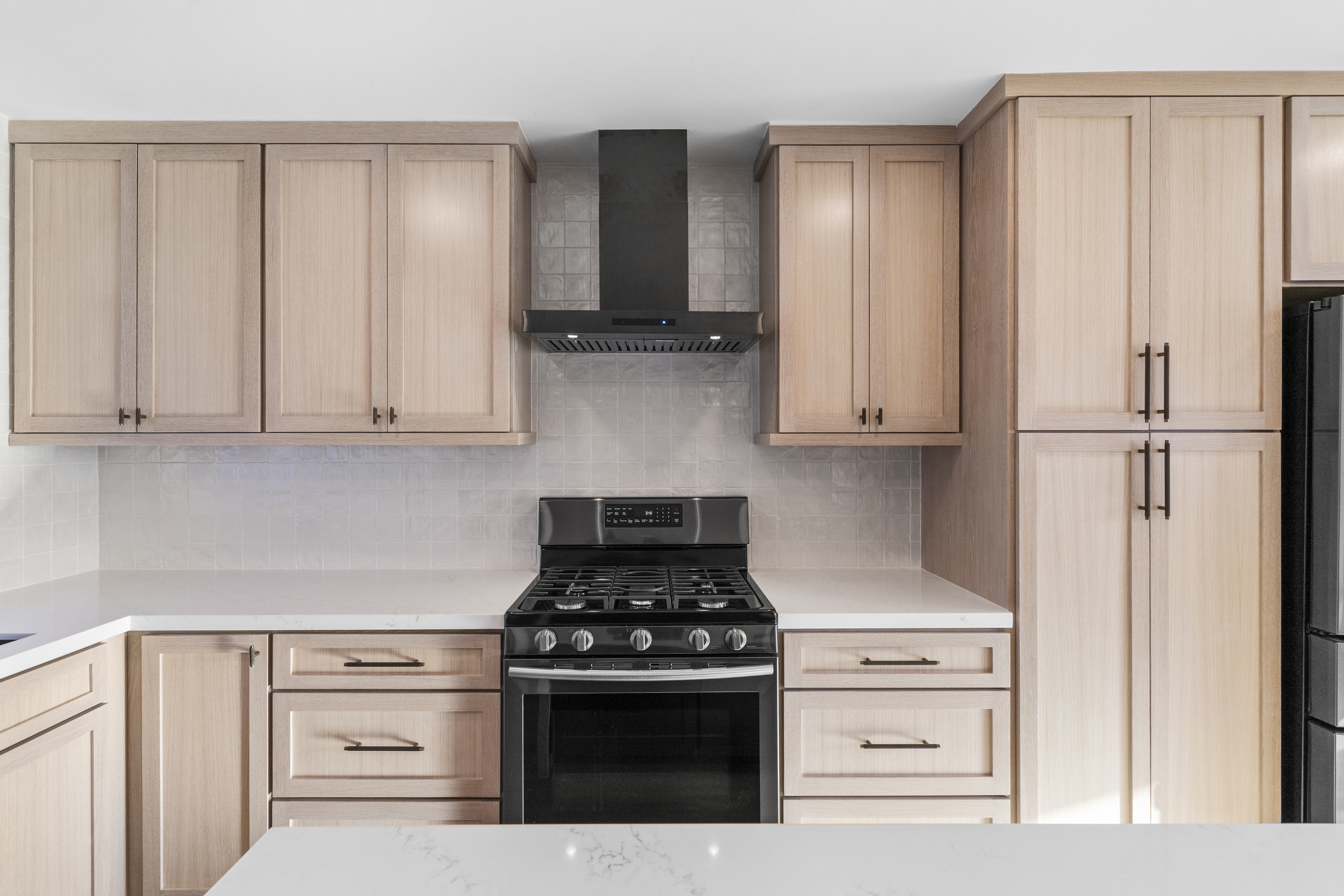 Light wood shaker cabinets with black handles