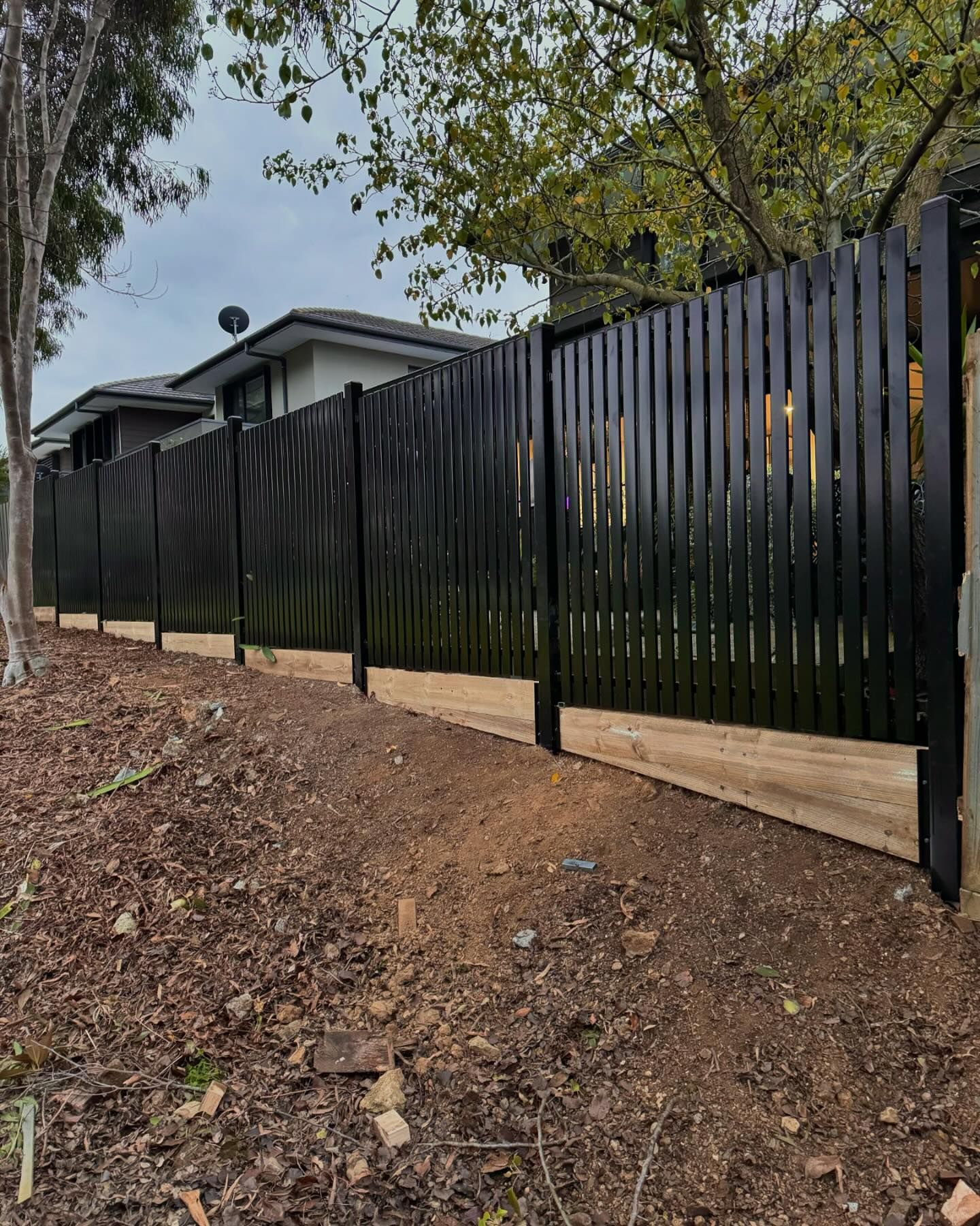 Black picket fence along sloped terrain