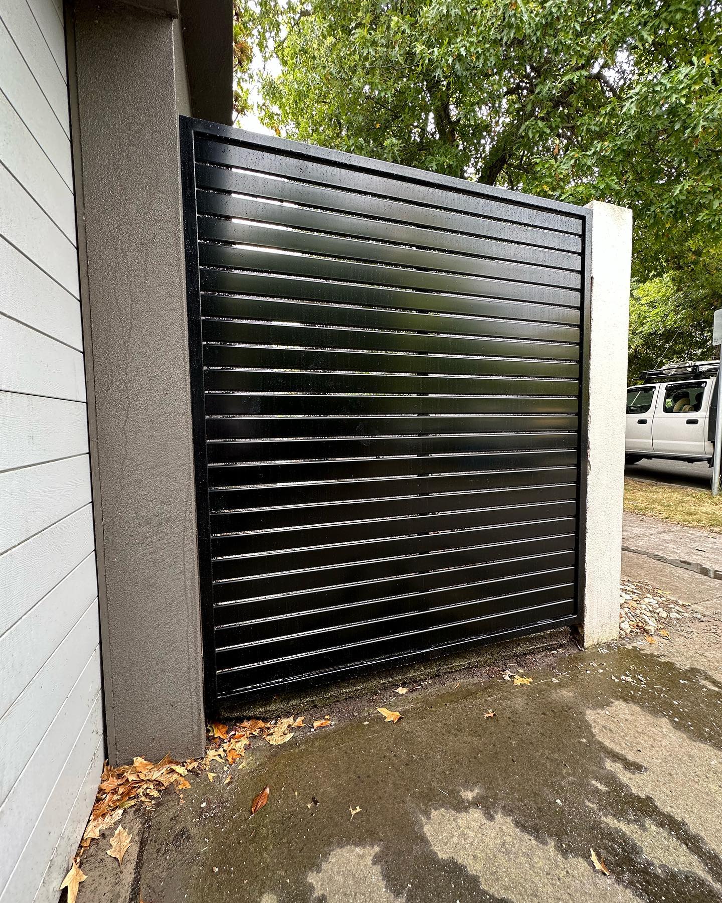 Black slat fence gate between textured walls