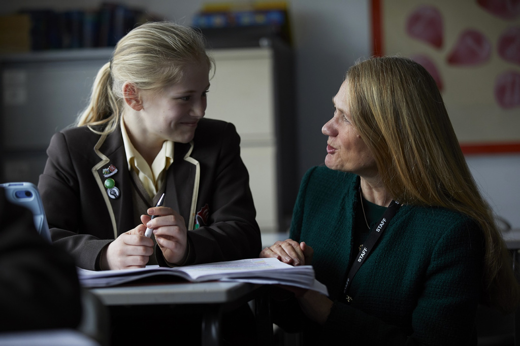 Engaged student and teacher conversing amidst learning materials in a classroom setting