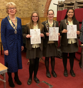 Young debaters proudly displaying their certificates alongside an authoritative figure
