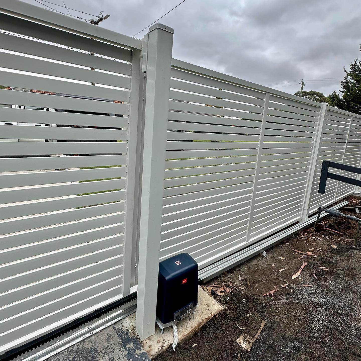 White painted steel slat fencing with automated sliding gate mechanism