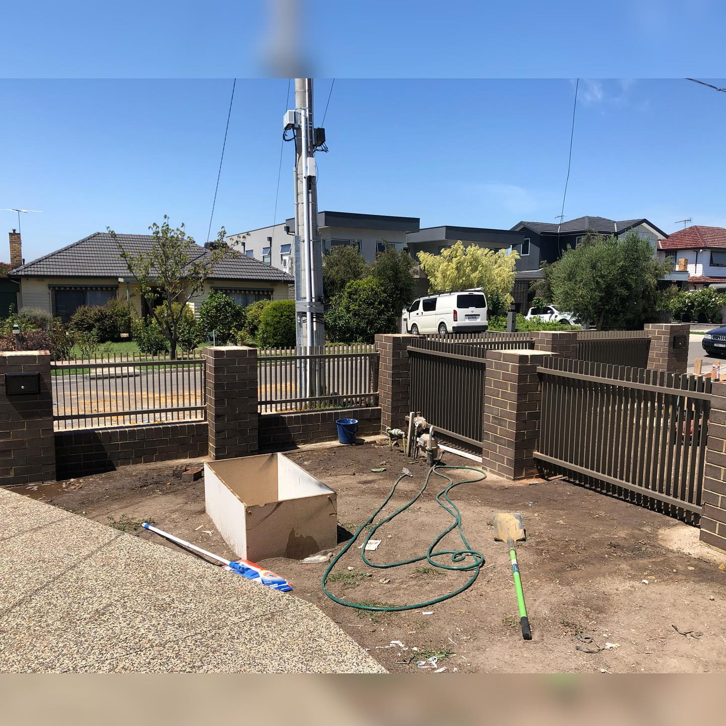 Modern Jasper Powder-Coated Blade Fence Enhances Twin Townhouse Development in Strathmore 3 Blade fence installed between brick pillars during construction