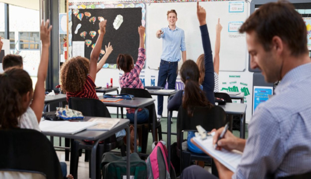 A classroom scene exemplifying peer observation with students participating actively and an observer taking notes discretely.