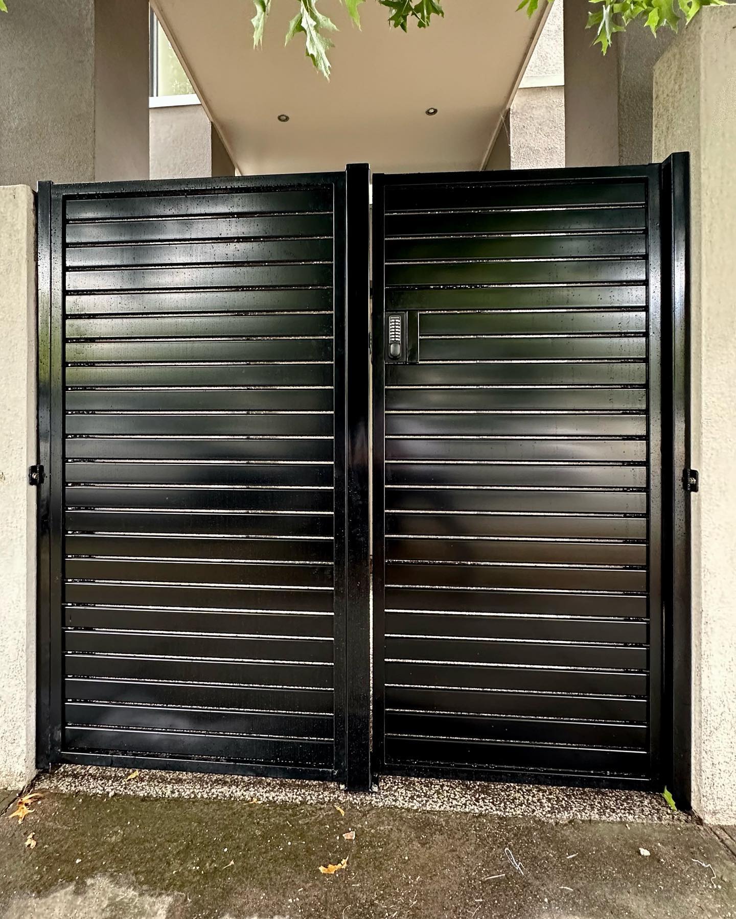 Two-panel black slat fence gate with keypad entry system