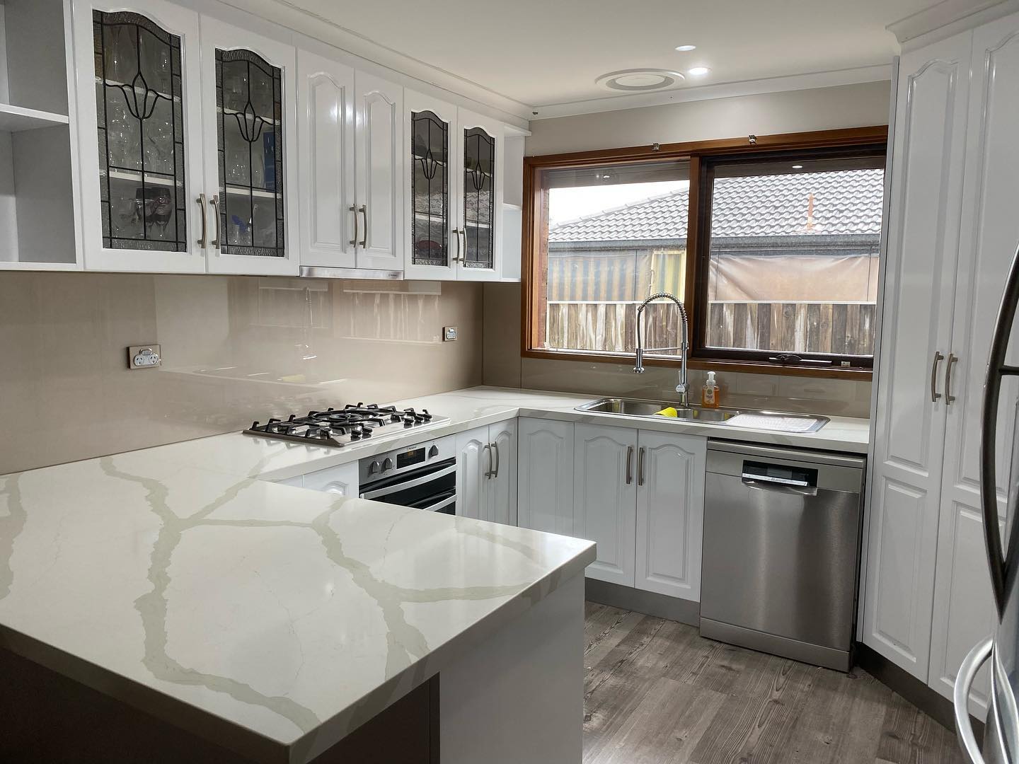 White cabinetry with glass-paneled doors and stainless steel appliances