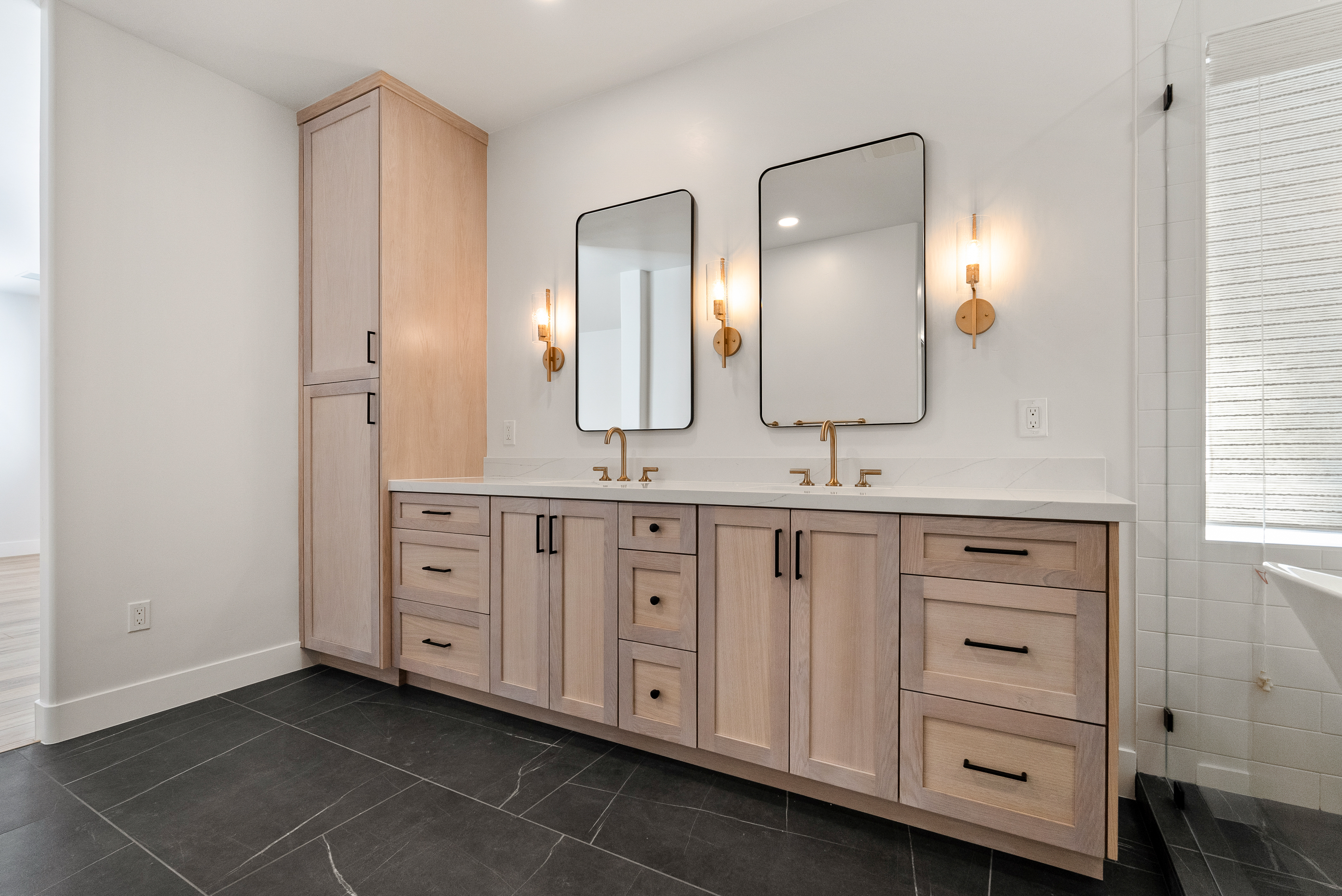 Double vanity with light wood cabinets and gold fixtures