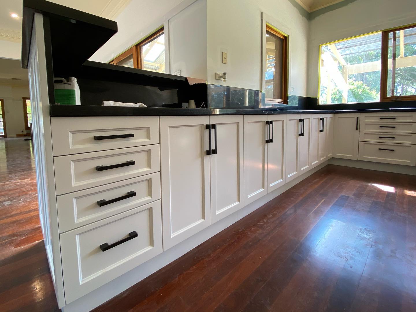 Modernized white kitchen cabinets with black handles arranged in an L-shape