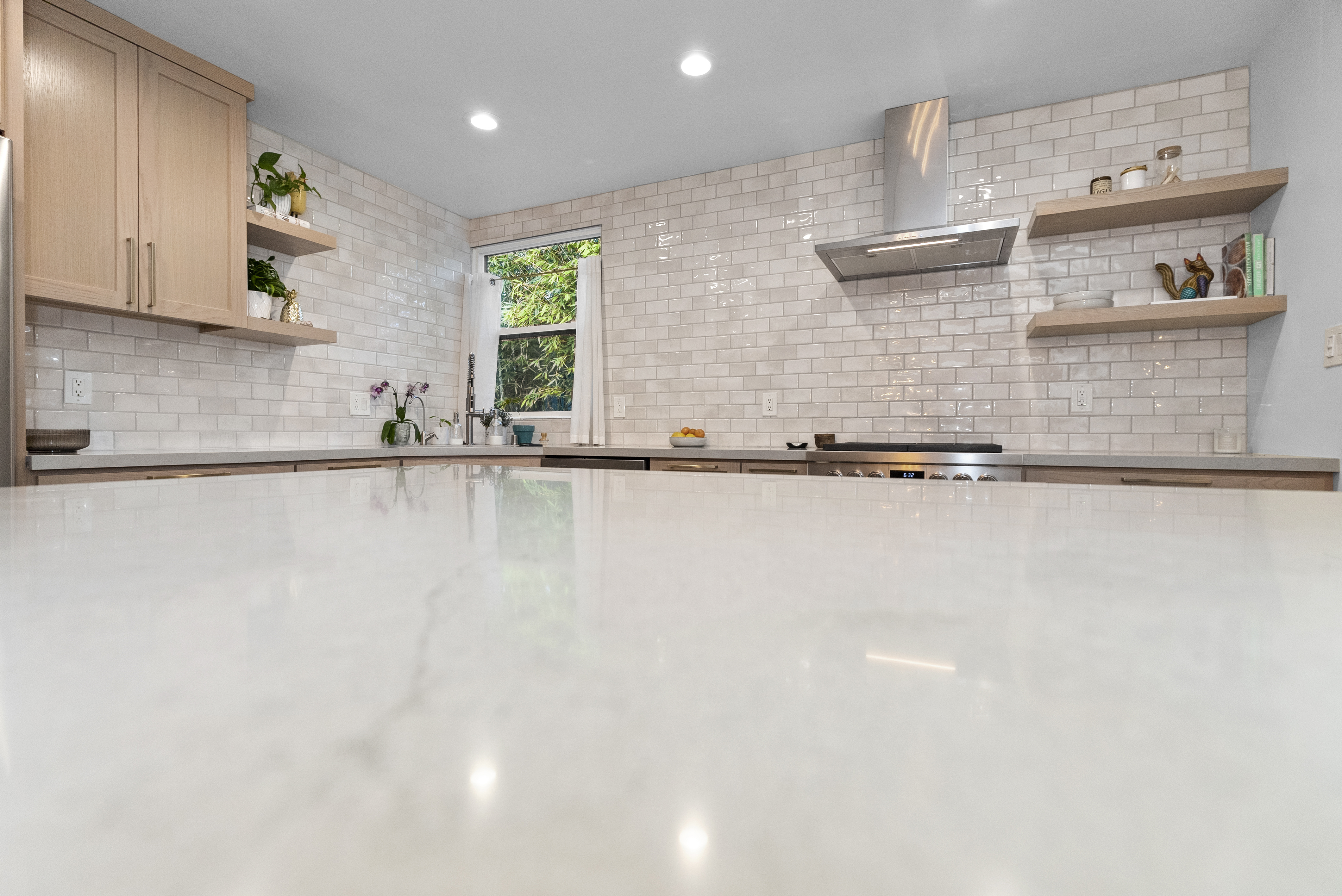 Light wood cabinetry with open shelving in remodeled kitchen