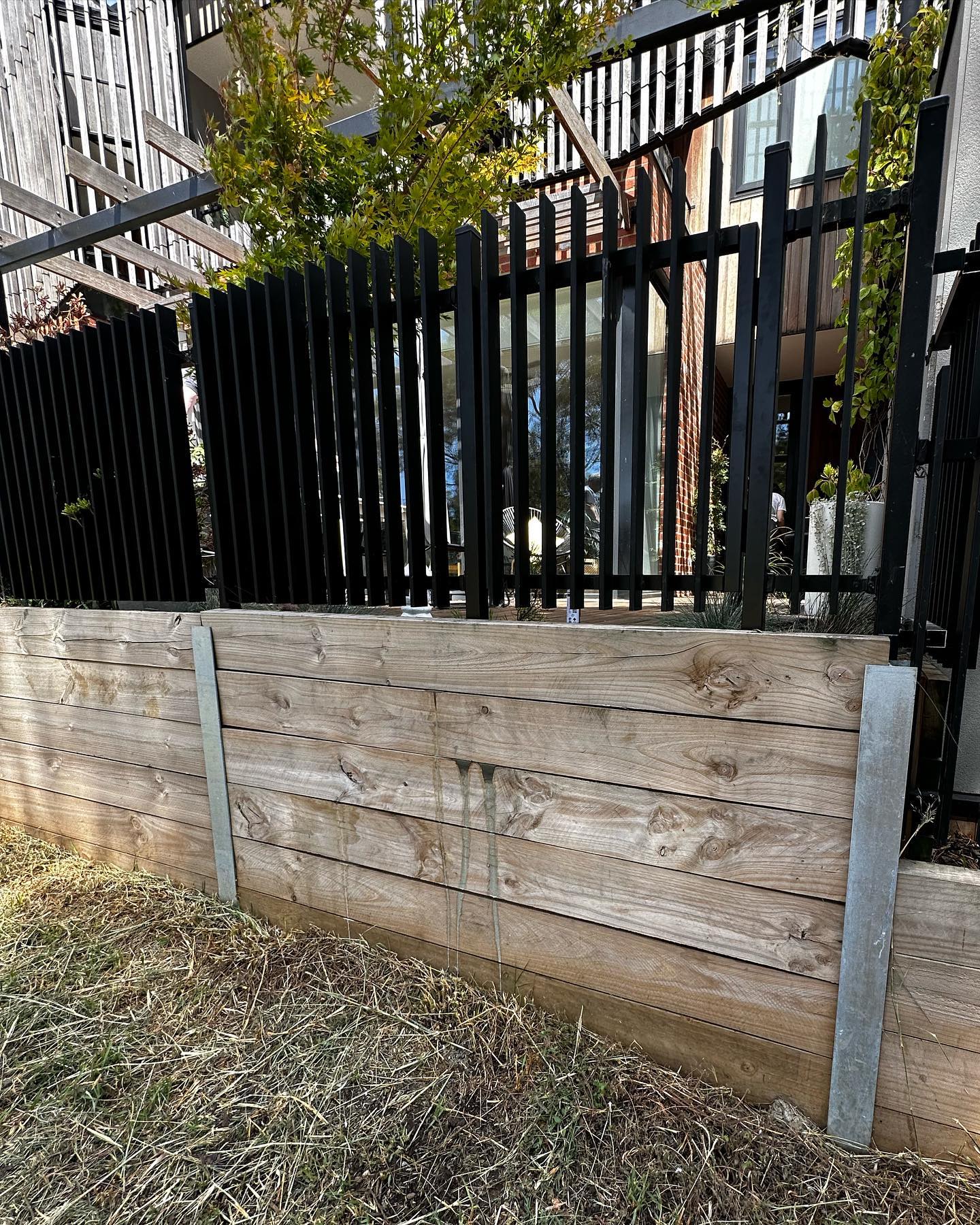 Creating Secure Park Access for a Northcote Townhouse 3 Black vertical metal fence panels with wooden retaining wall
