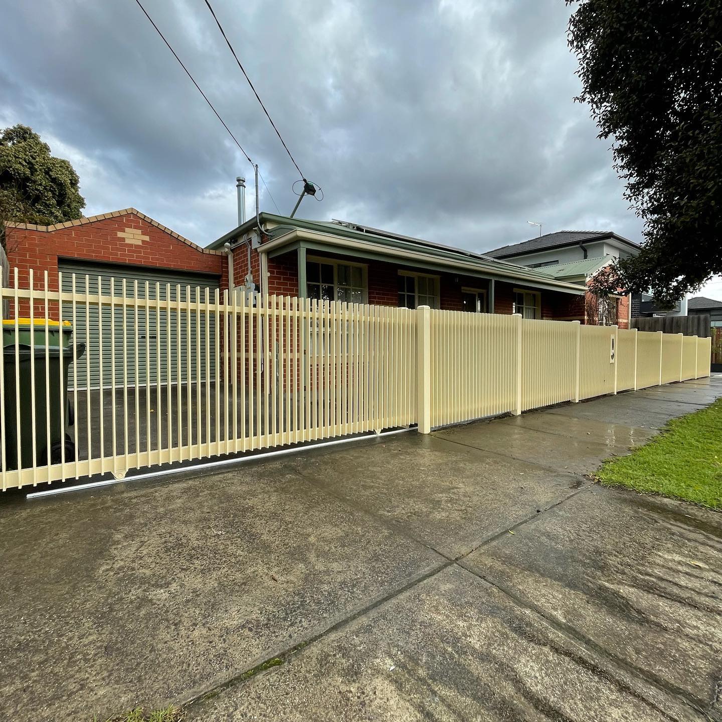 Beige metal fence spanning residential driveway