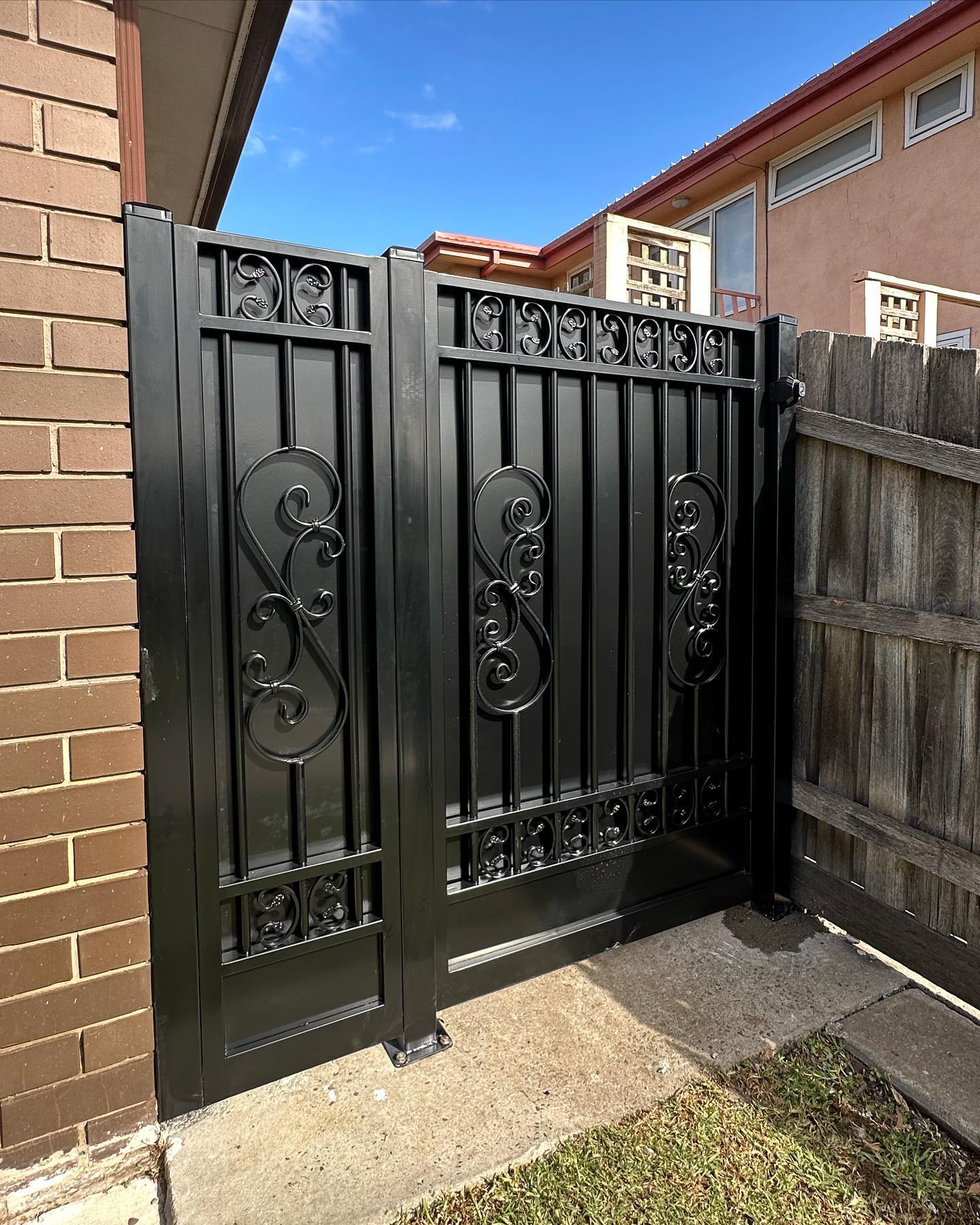 Two black Custom Gates in Keilor with intricate infill panels featuring scrollwork designs