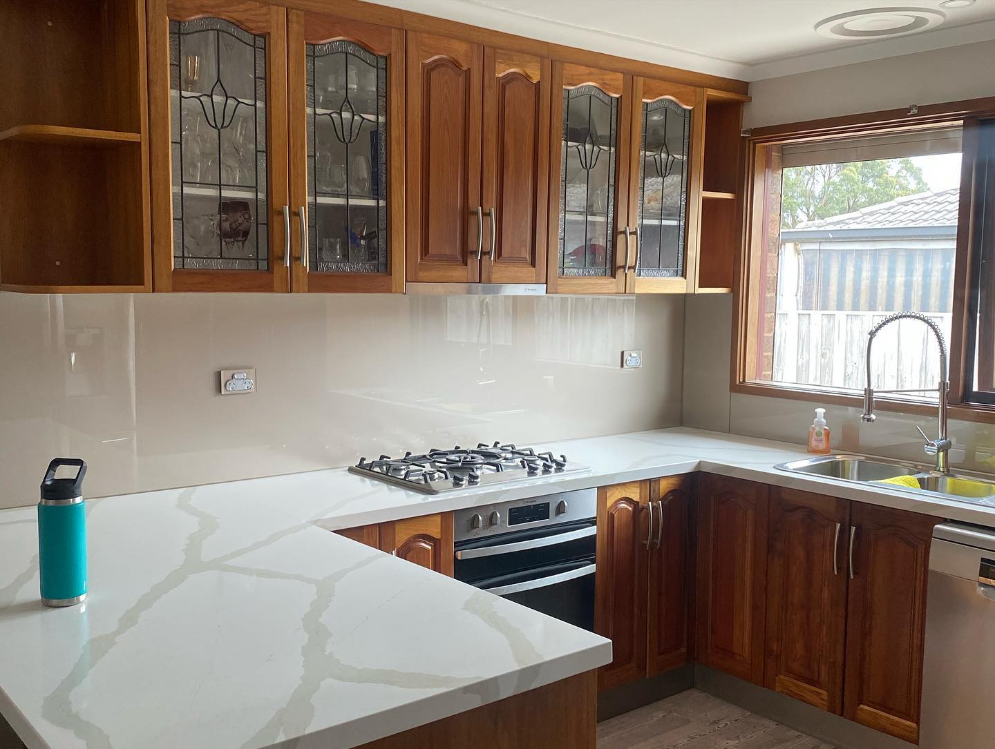 Wooden cabinetry with glass-paneled doors and white marble countertops
