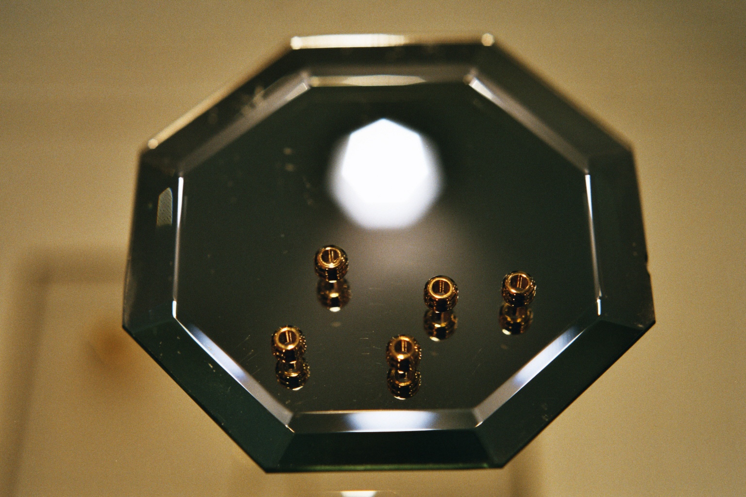 Abstract image showing brown spheres on a mirror surface with a blurred light source in the background