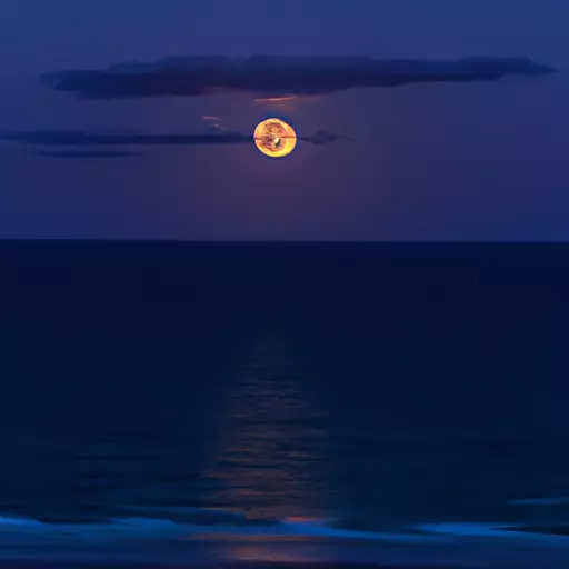 A picture of the moon rising over the ocean