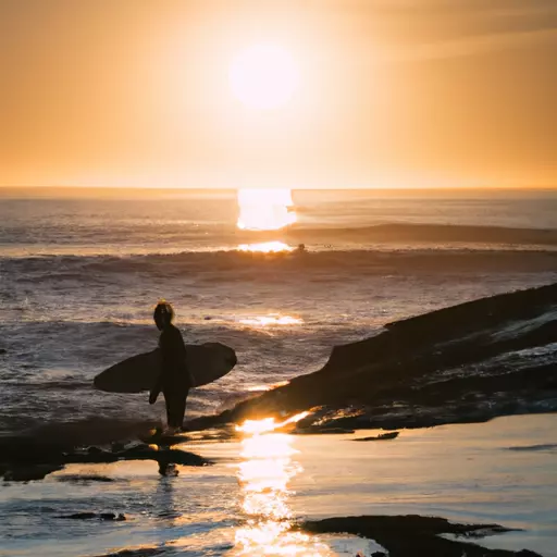 A picture of a surfer in the ocean with the sun in the background