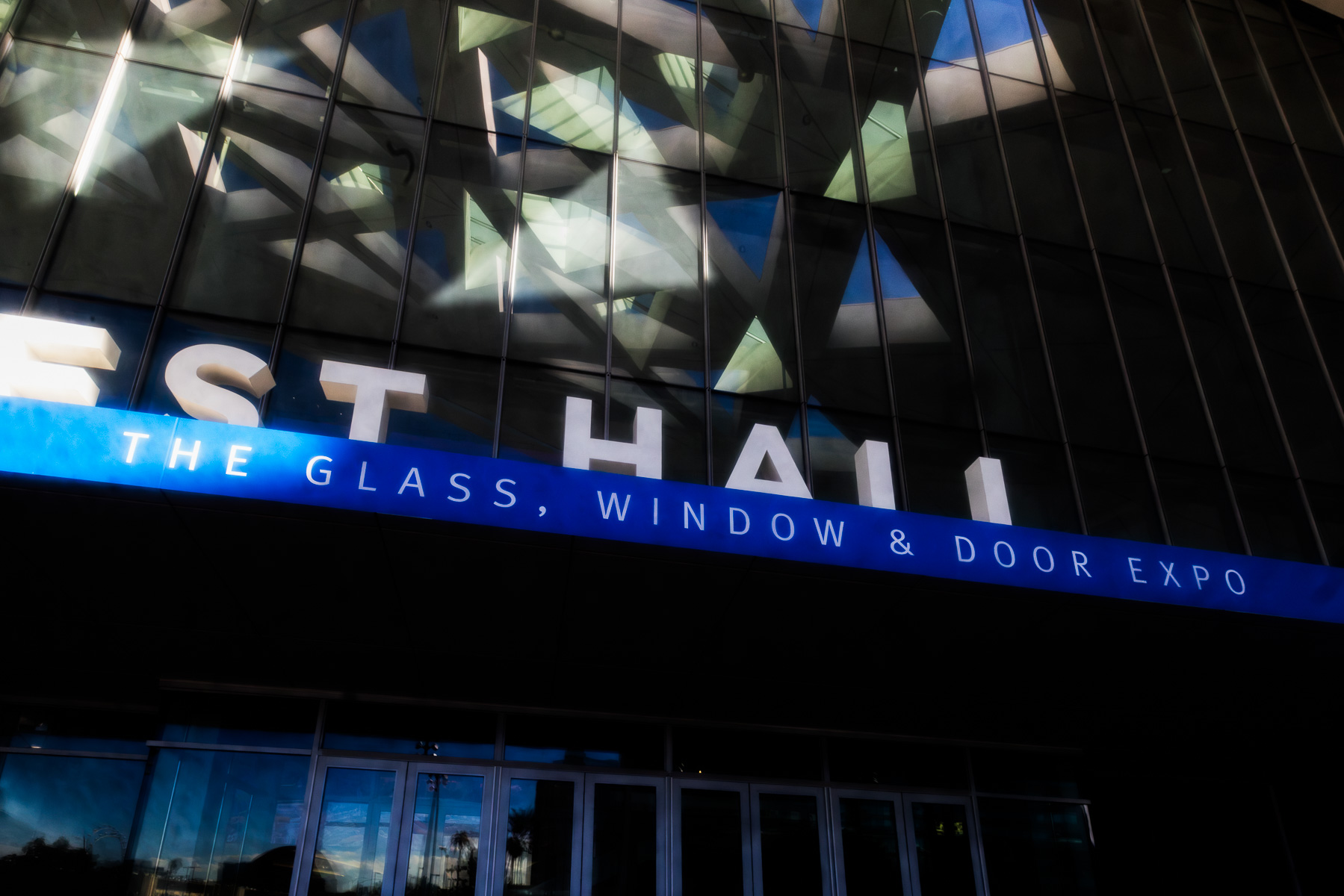 A close-up of the "WEST HALL" sign and "THE GLASS, WINDOW & DOOR EXPO" banner on the convention center facade.