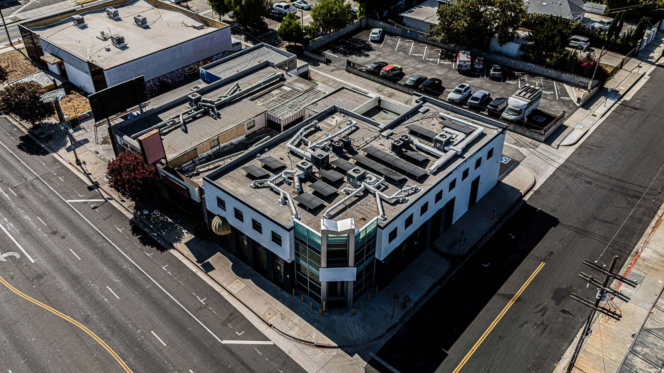 An aerial view of a commercial building at a street corner featuring a newly installed glass curtainwall.