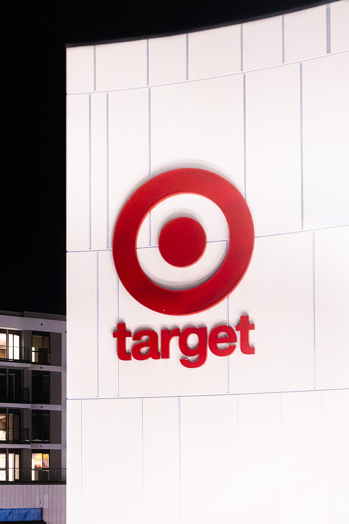 A close-up shot of the red Target bullseye logo and text on a white building facade at night.