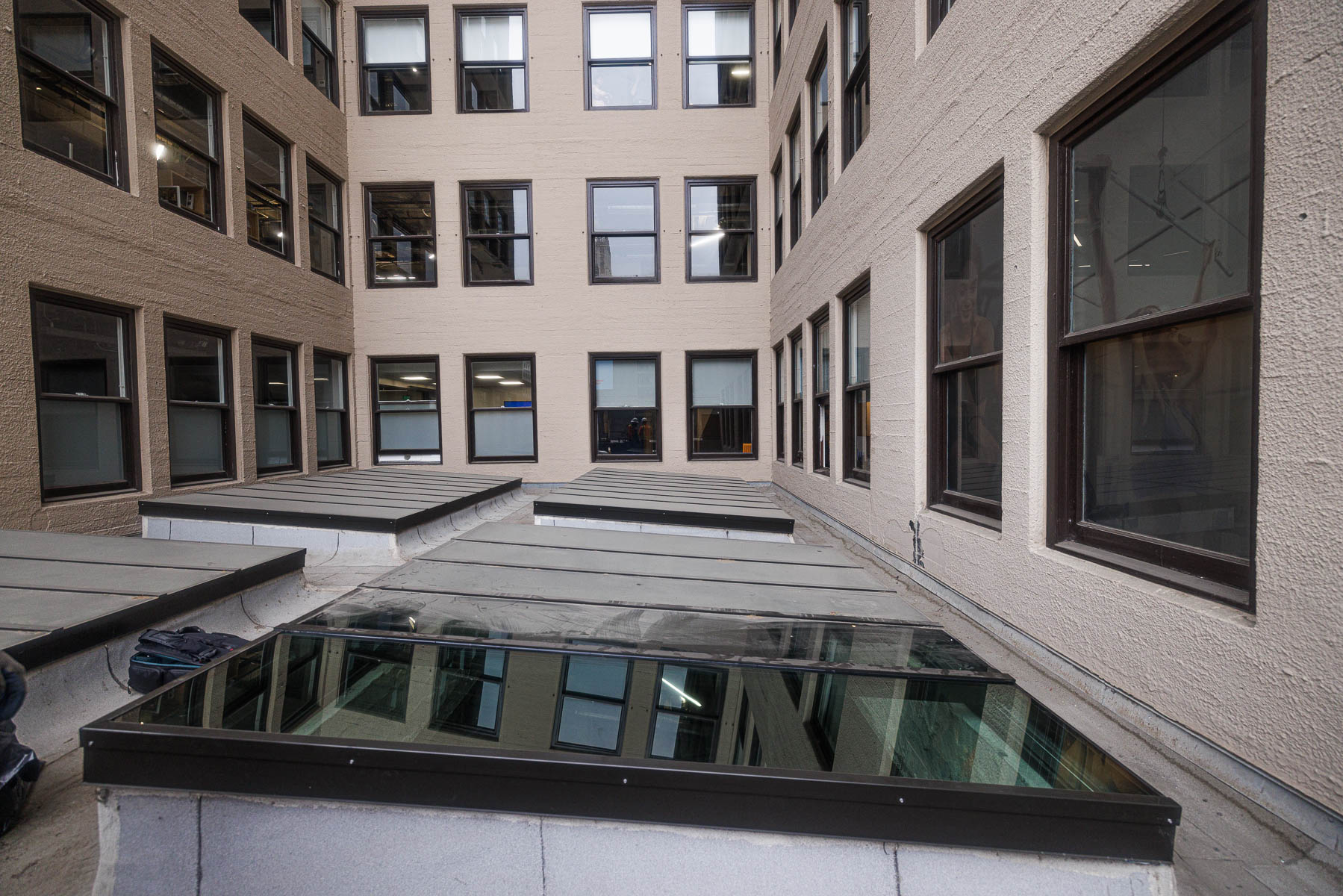An exterior view of a commercial building's courtyard with multiple skylights and surrounding windows.