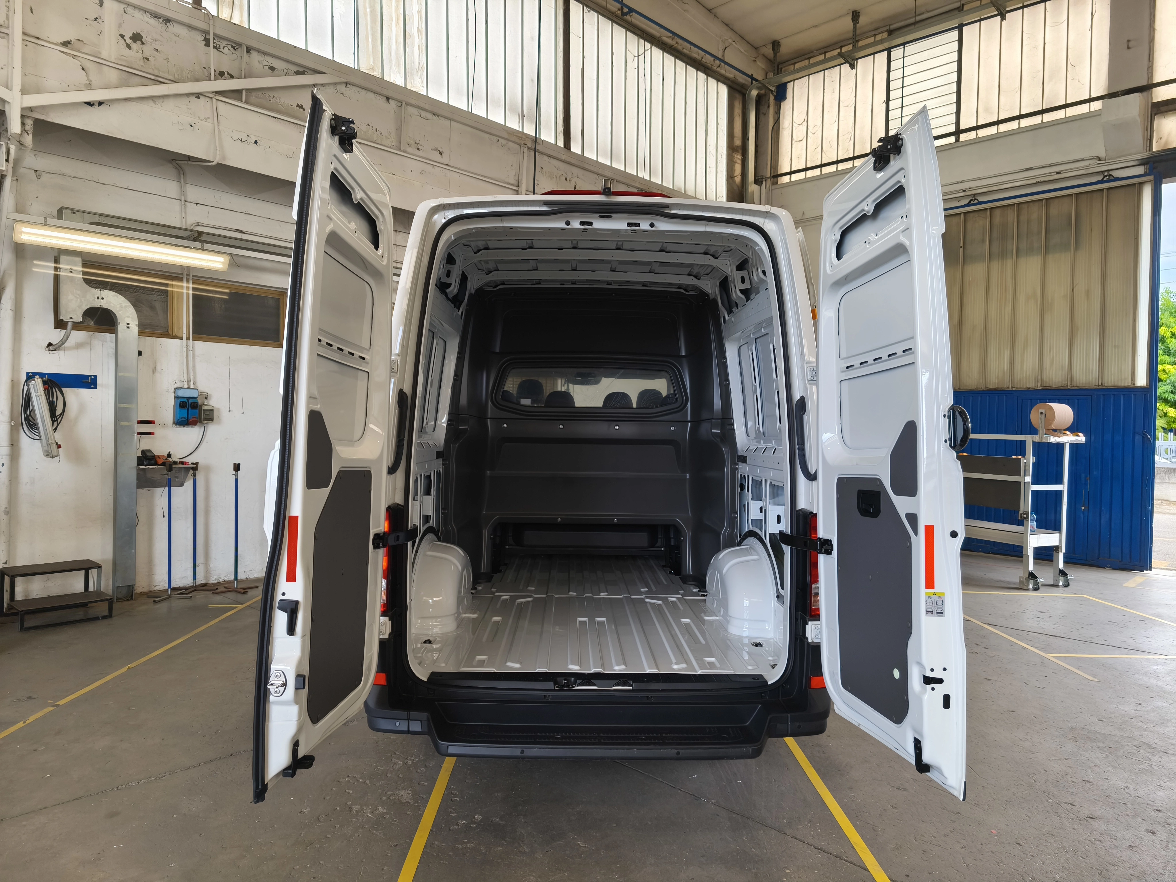 Vista posteriore di un furgone bianco con le portiere posteriori aperte.