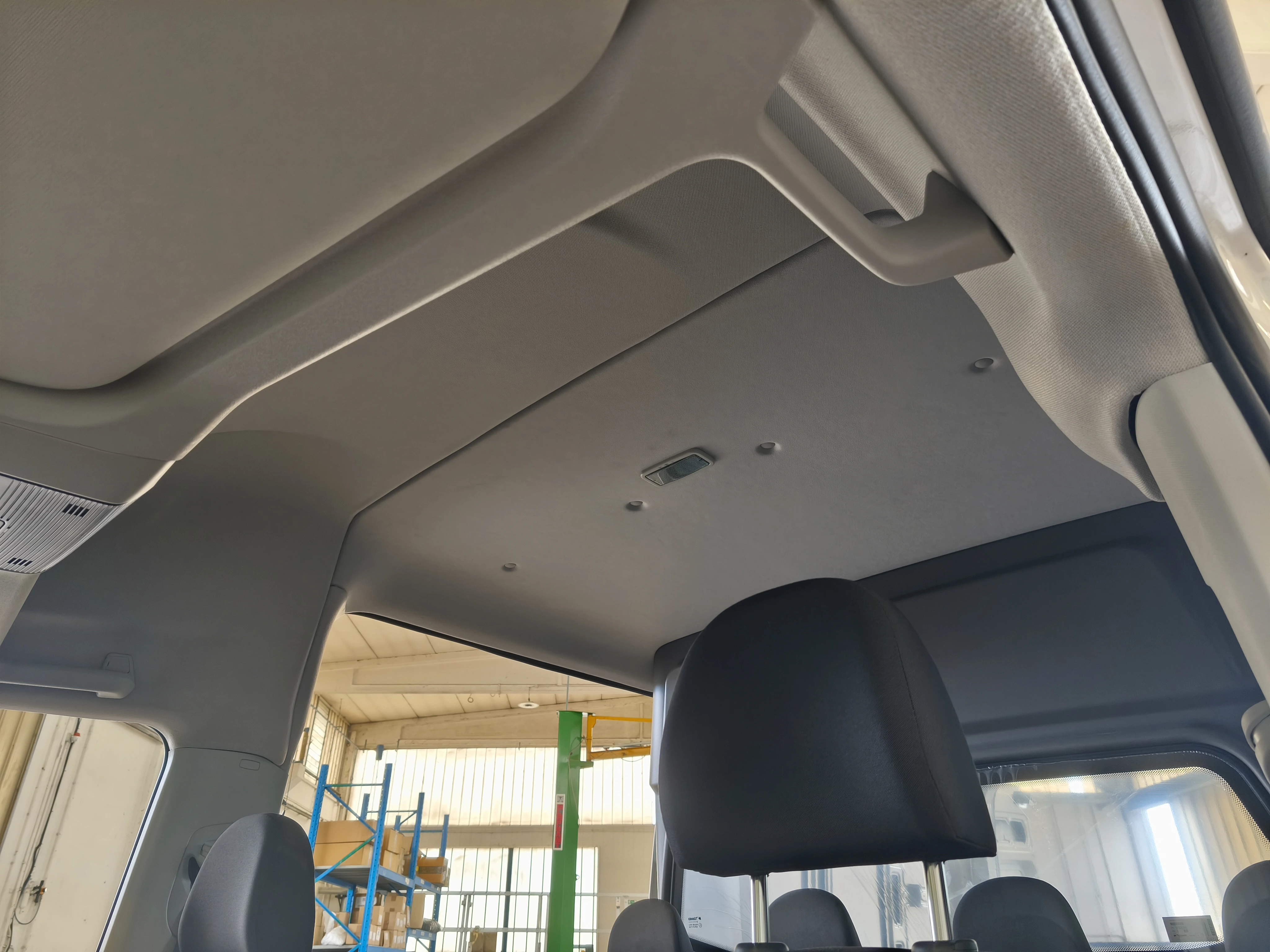 Interno di un'auto che mostra la tappezzeria del tetto, i sedili anteriori e il parabrezza posteriore.