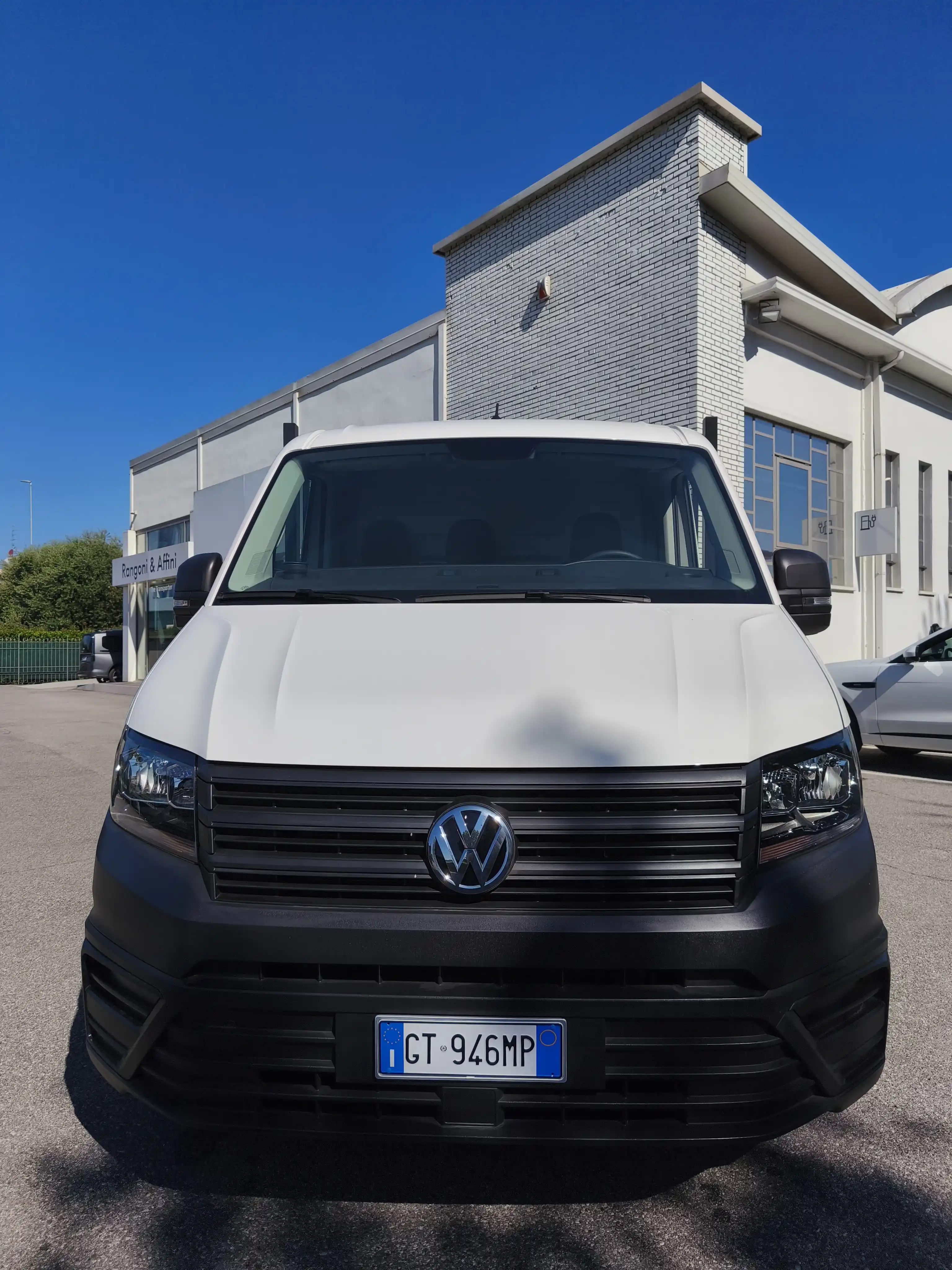 Furgone bianco Volkswagen parcheggiato davanti a un edificio bianco.