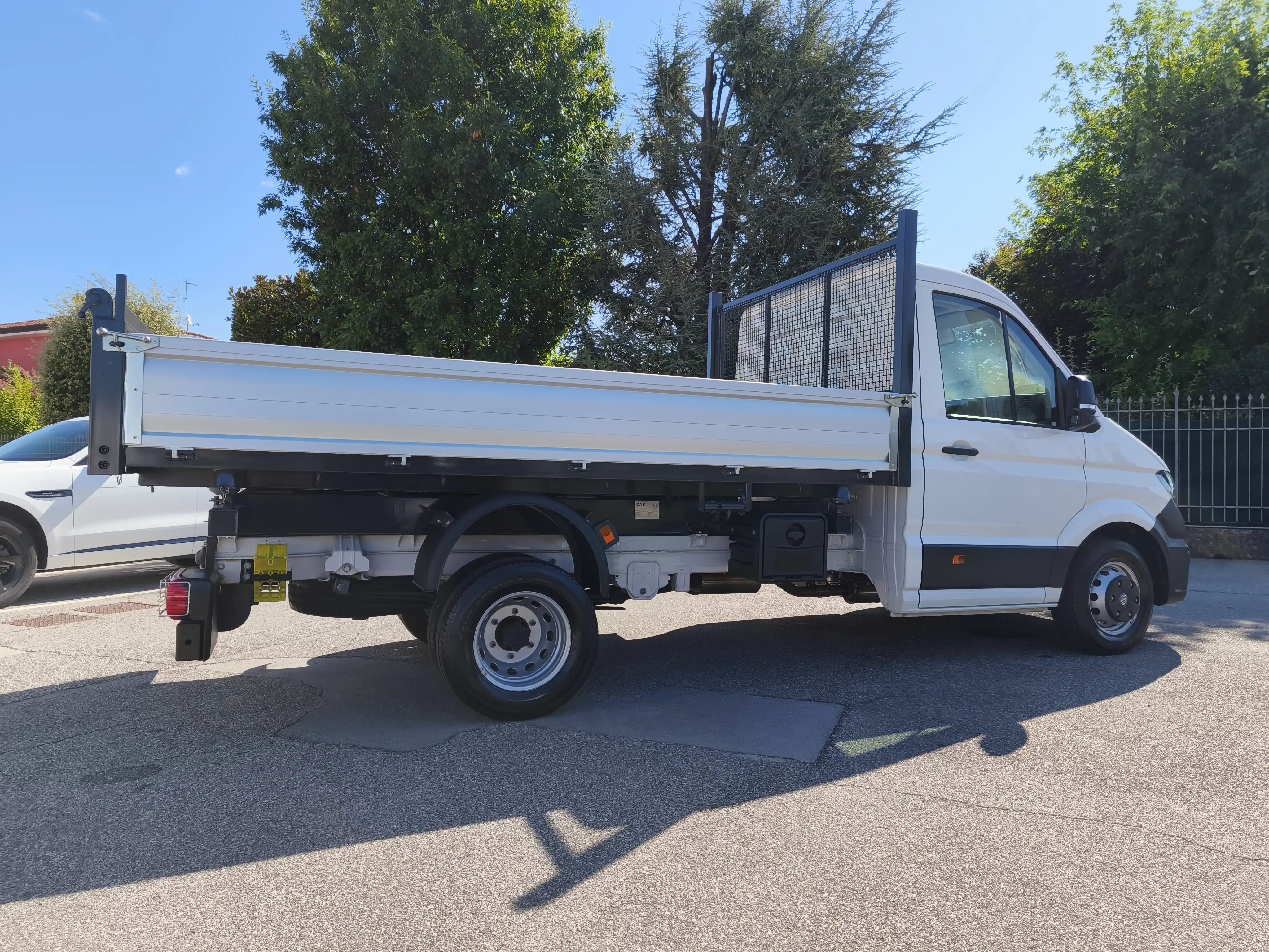 Un camioncino bianco parcheggiato in una strada di quartiere in una giornata soleggiata.