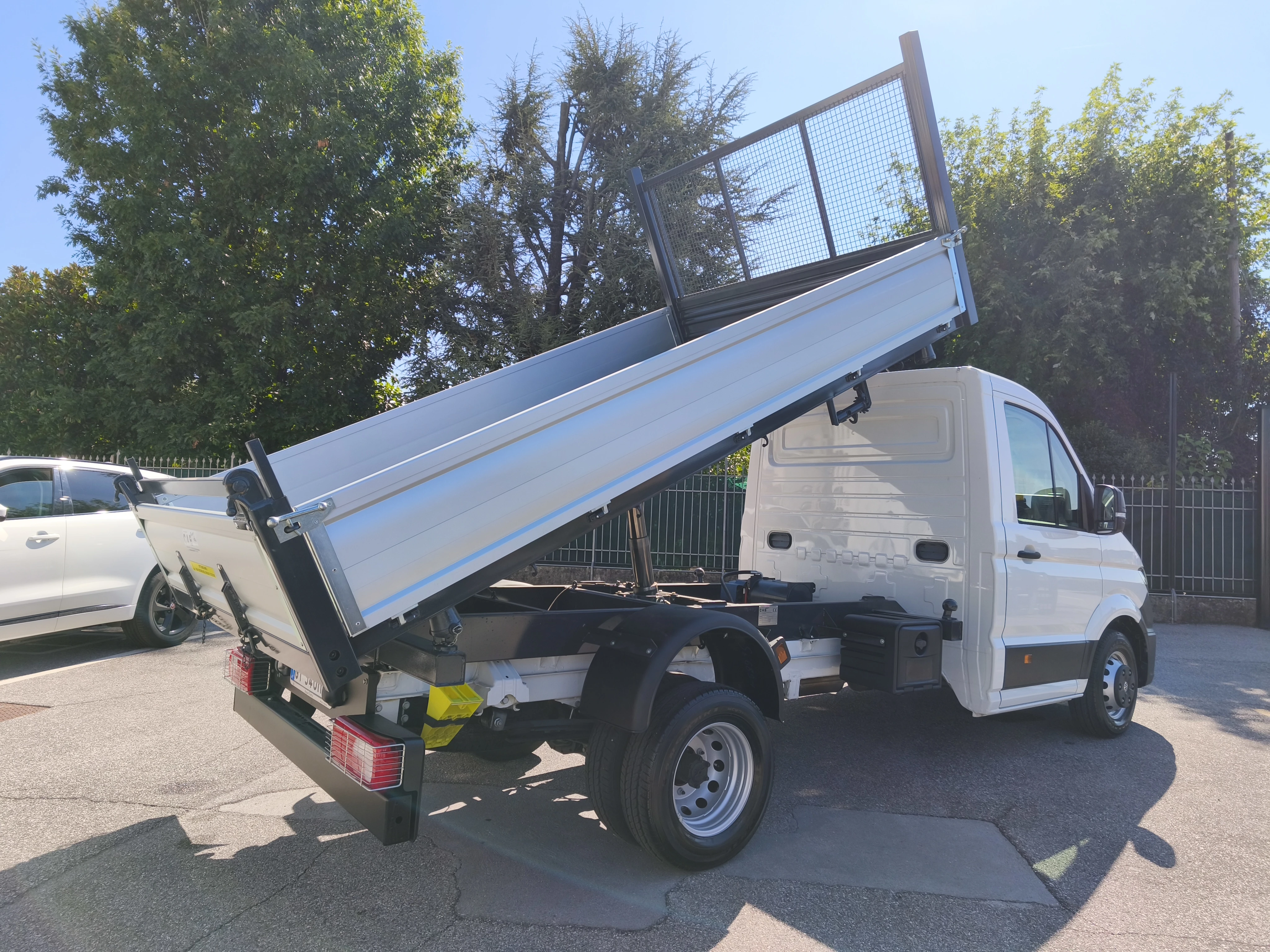 Un camion ribaltabile bianco parcheggiato all'esterno in una giornata di sole.