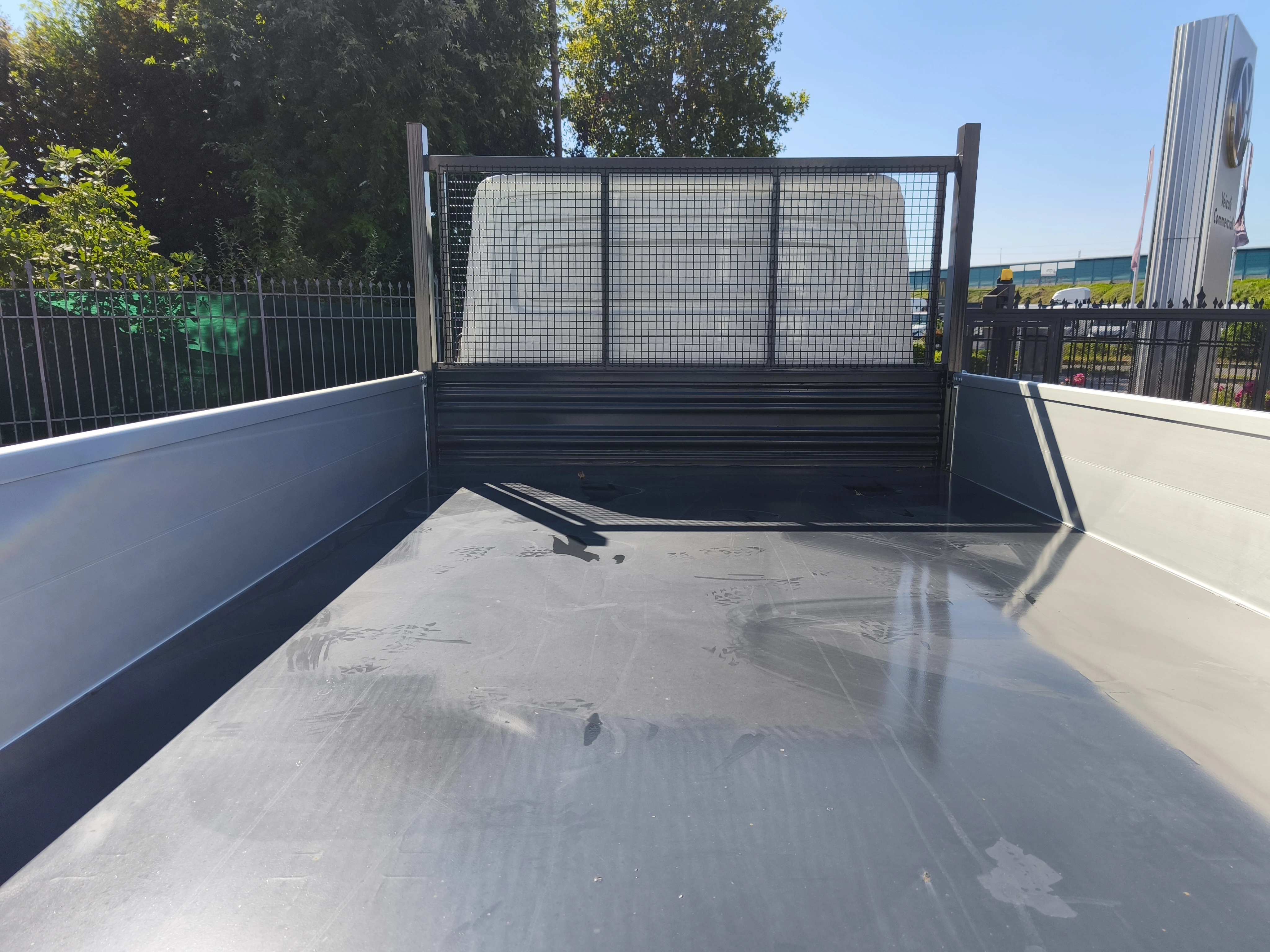 Cassone ribaltabile per autocarro con sponde laterali grigie e schermo in metallo sul retro.