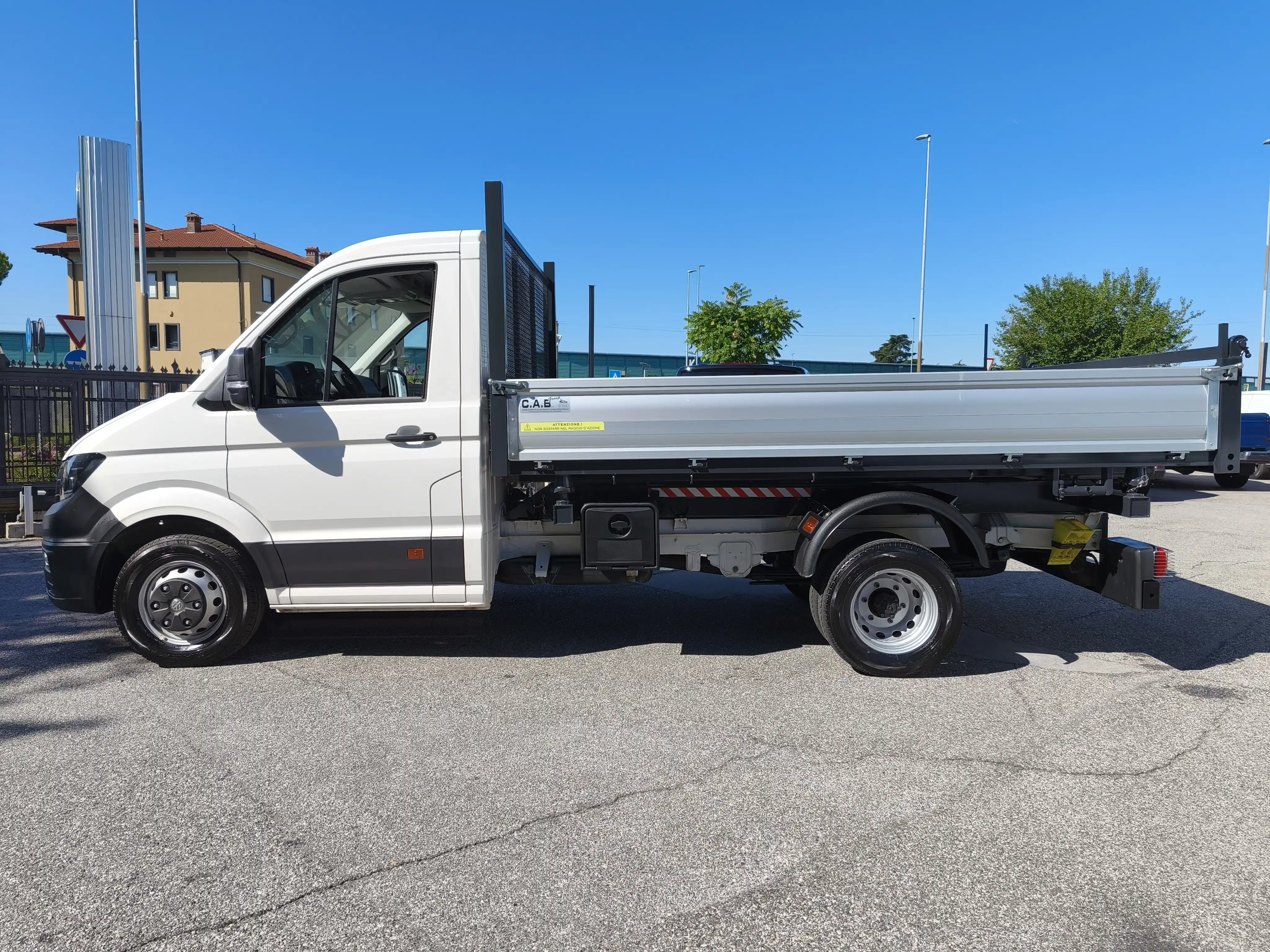 Camion bianco con cassone di carico su asfalto in una giornata di sole.