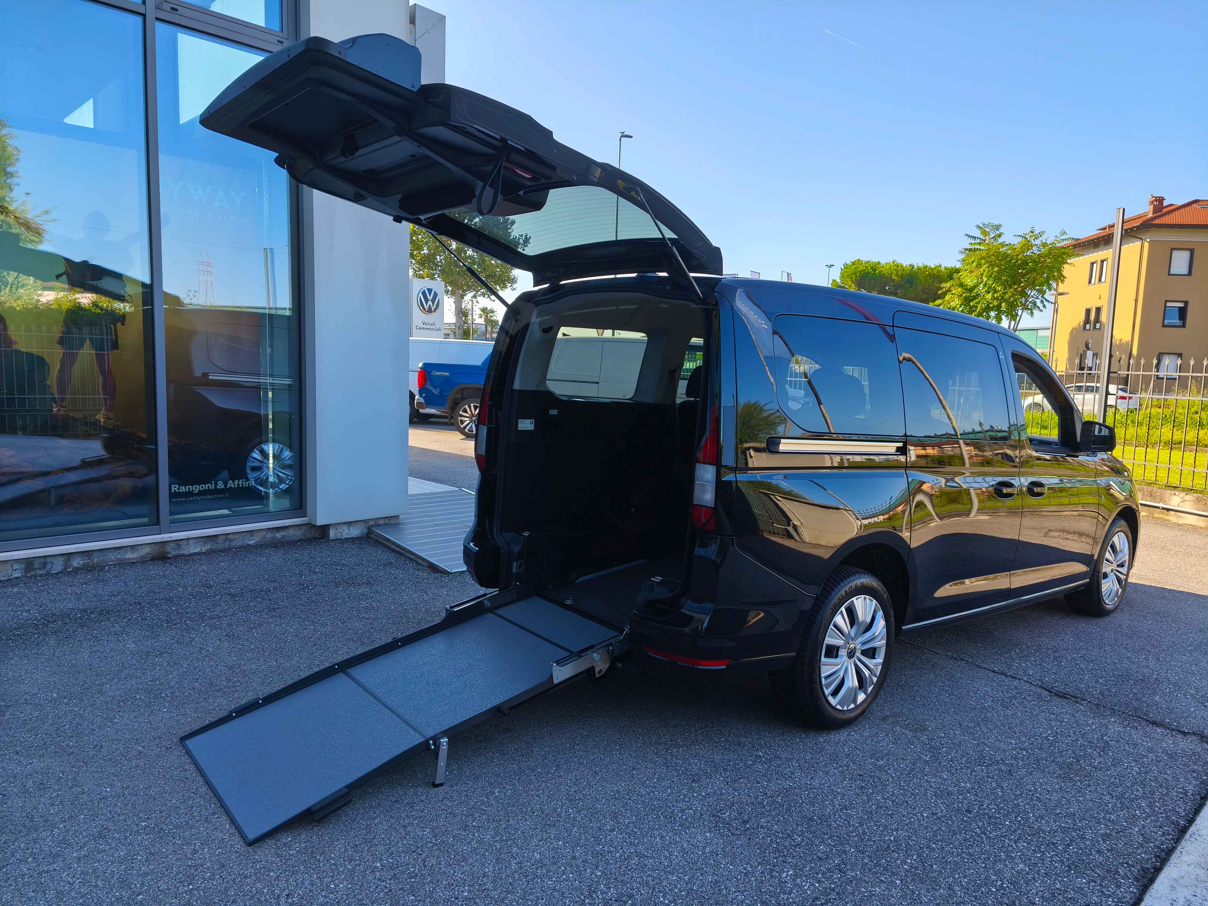 Un furgone nero con la rampa per sedie a rotelle estesa.