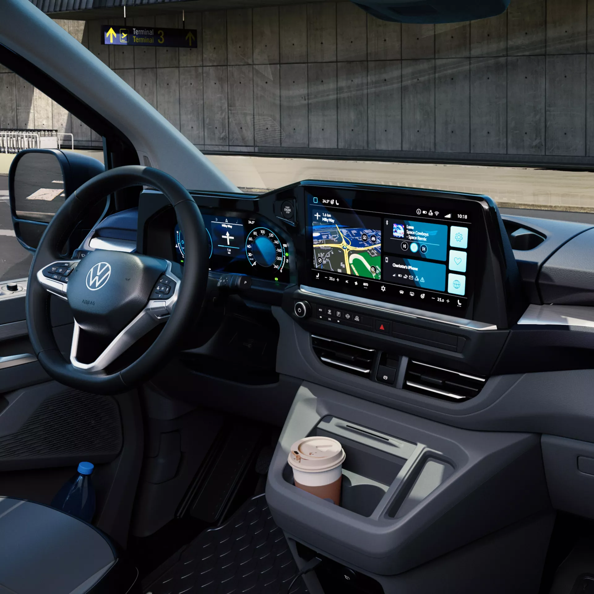 L'interno di un veicolo Volkswagen mostra un display digitale, un volante e un portabicchieri con un caffè.
