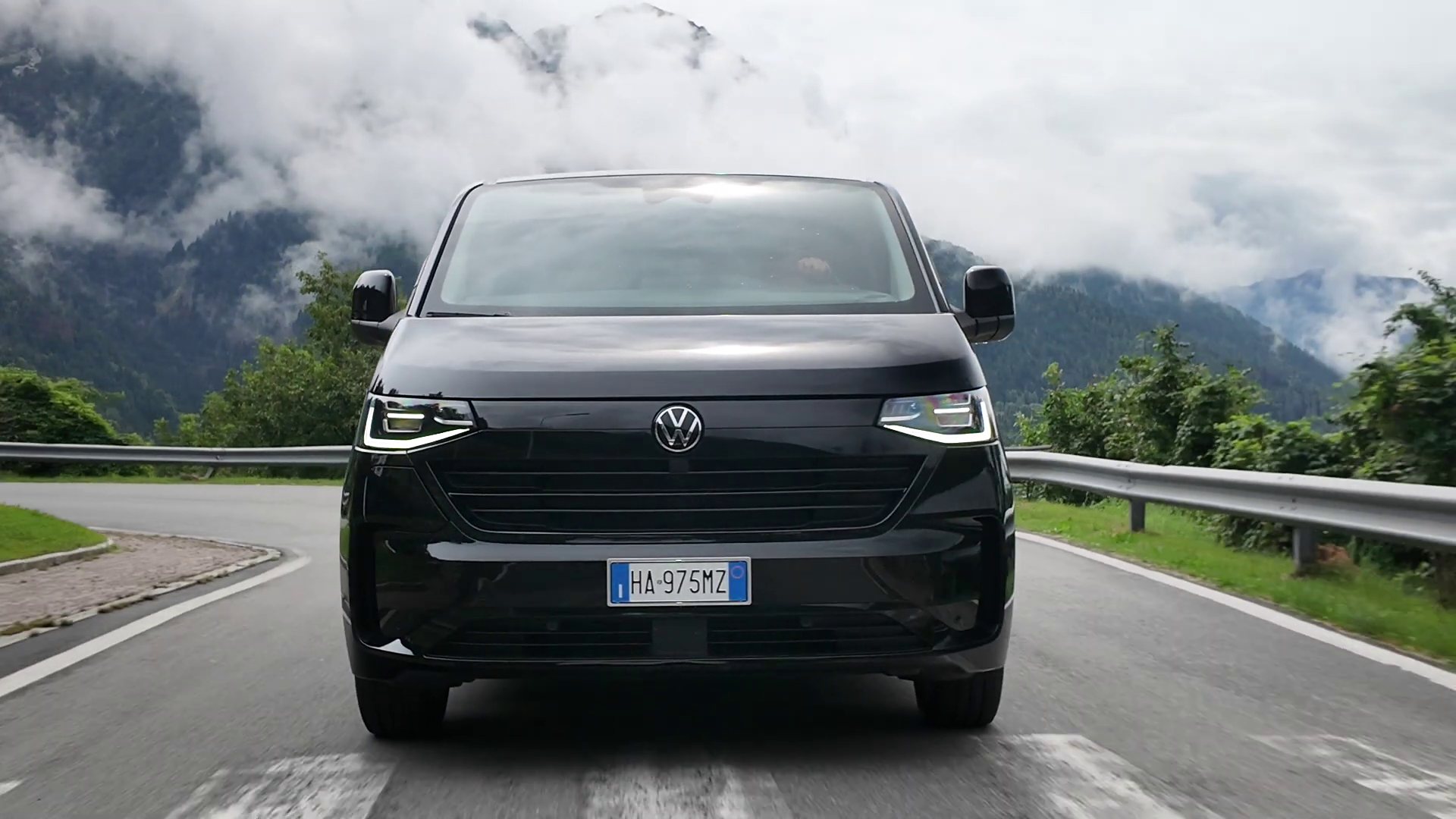 Un furgone nero Volkswagen in viaggio su una strada di montagna.