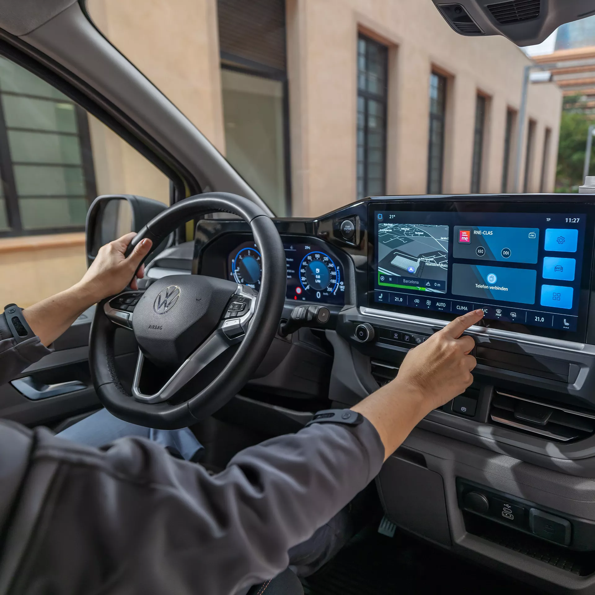 Interni dell'auto con conducente che interagisce con lo schermo di controllo.