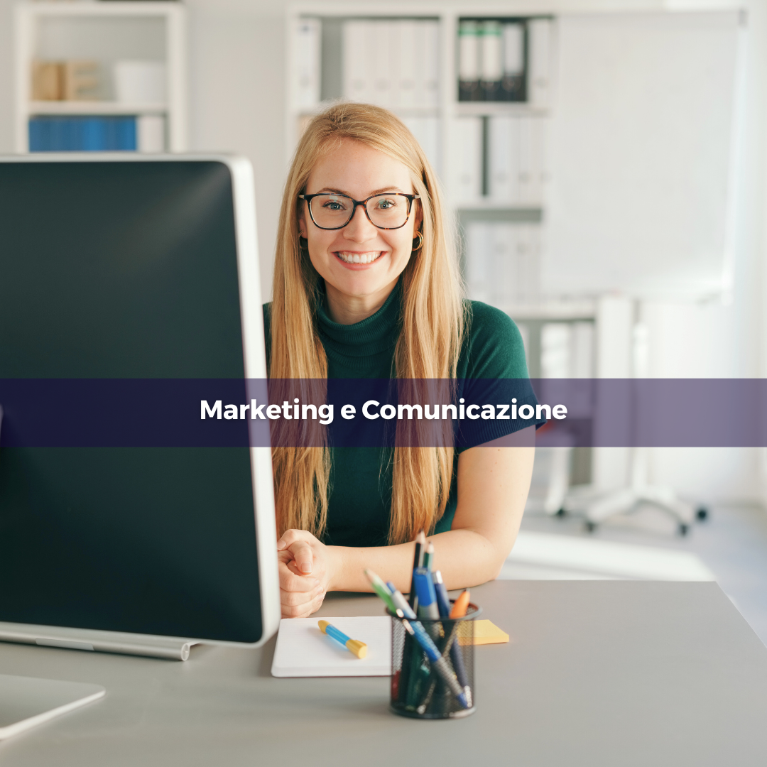 Una donna seduta alla sua scrivania sorride alla fotocamera.