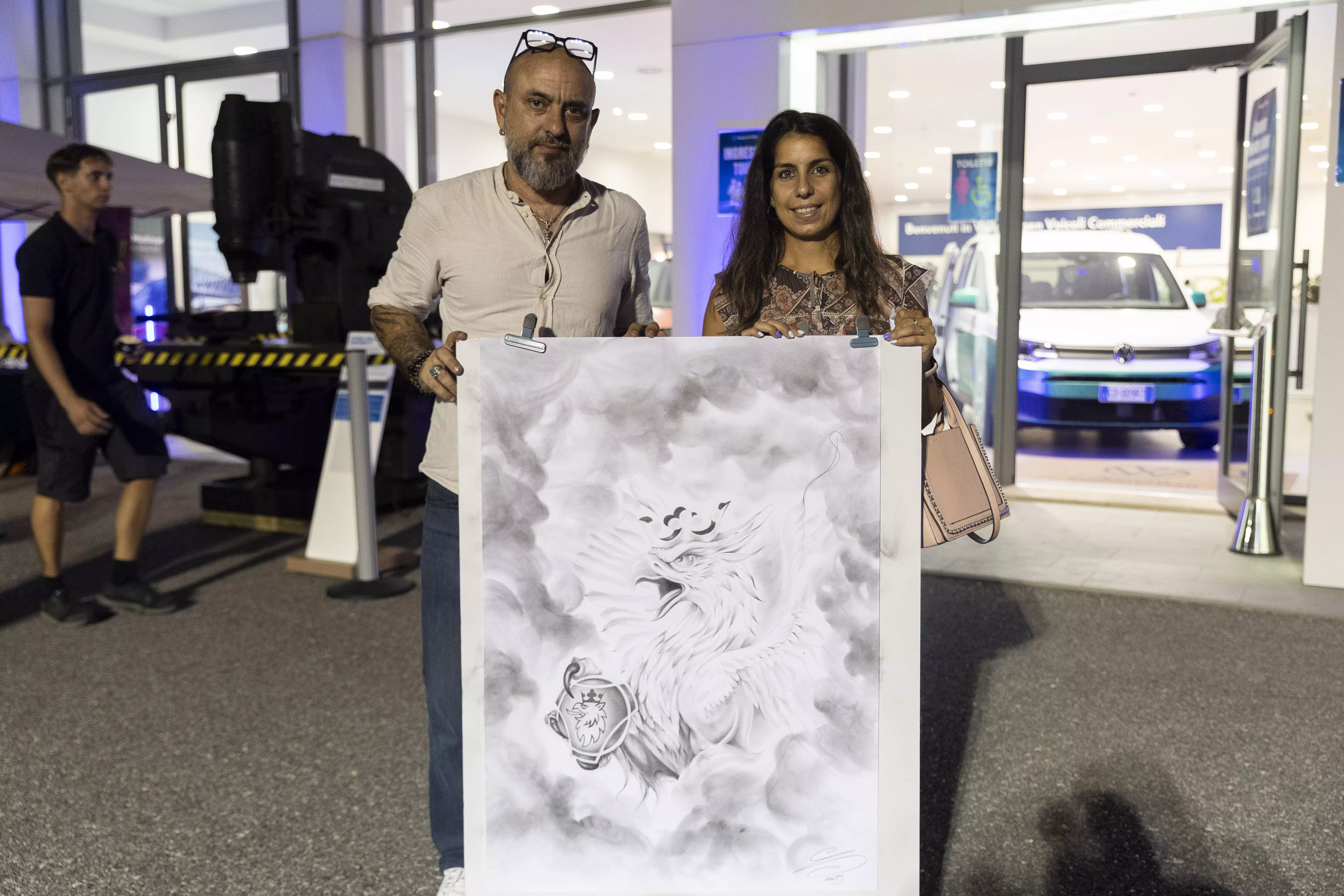Persone in posa con un disegno di una fenice di fronte a un edificio.