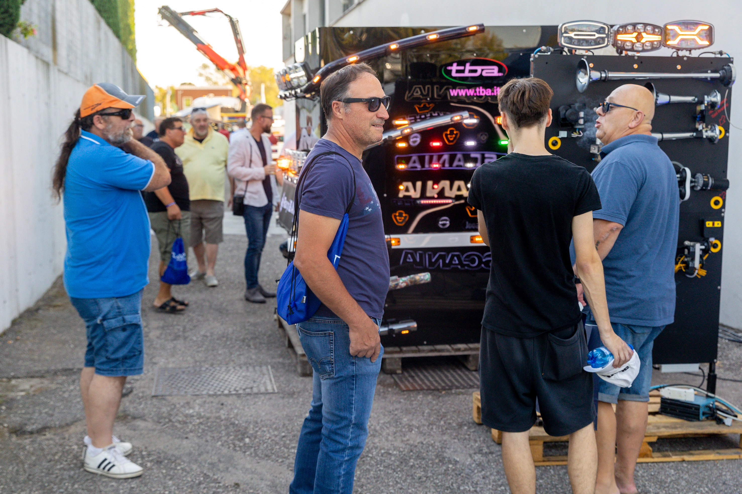 Una folla di persone è riunita intorno a un rimorchio con attrezzatura per camion a un evento all'aperto.