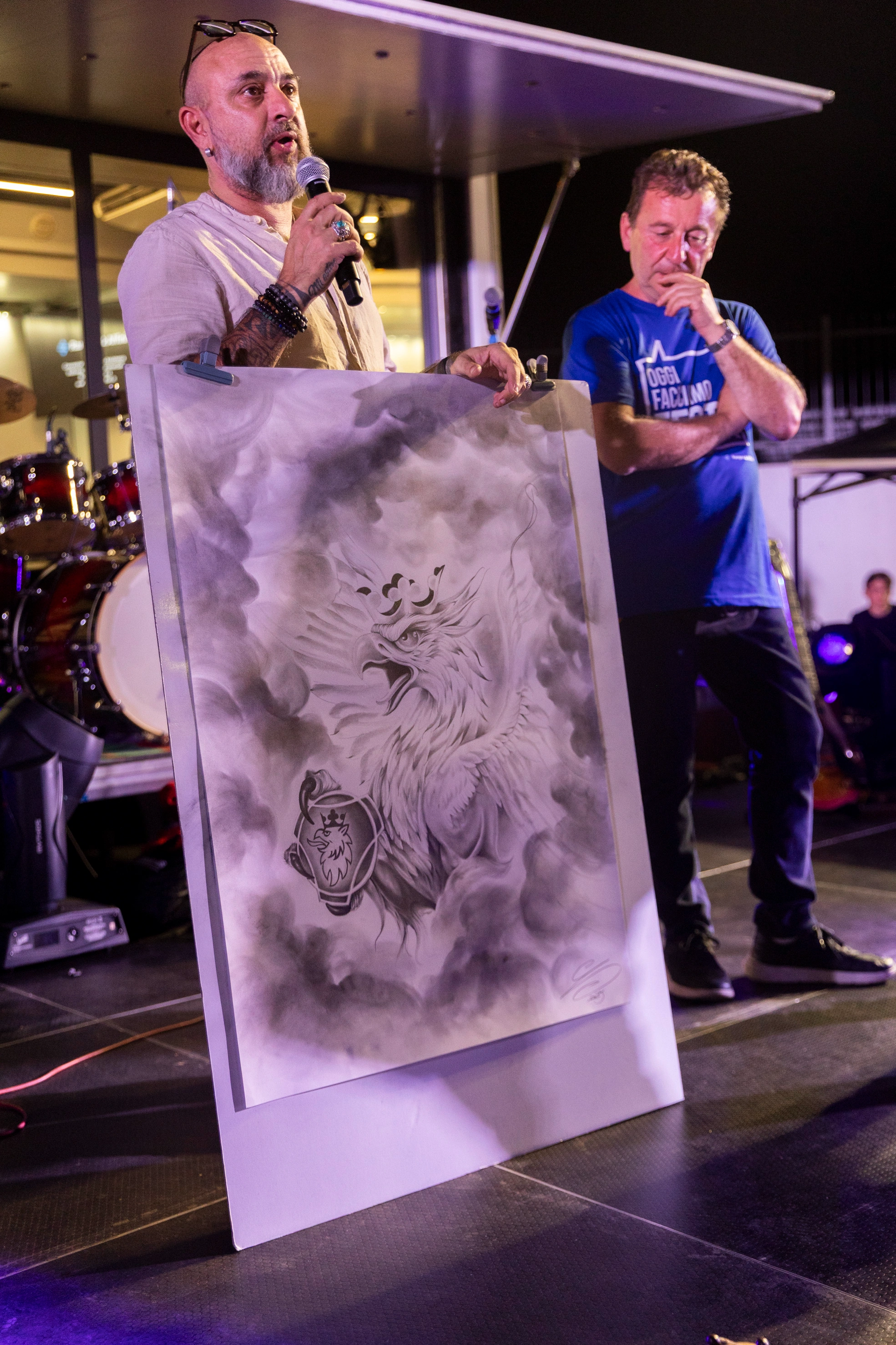 Artista che presenta il suo disegno di un grifone.