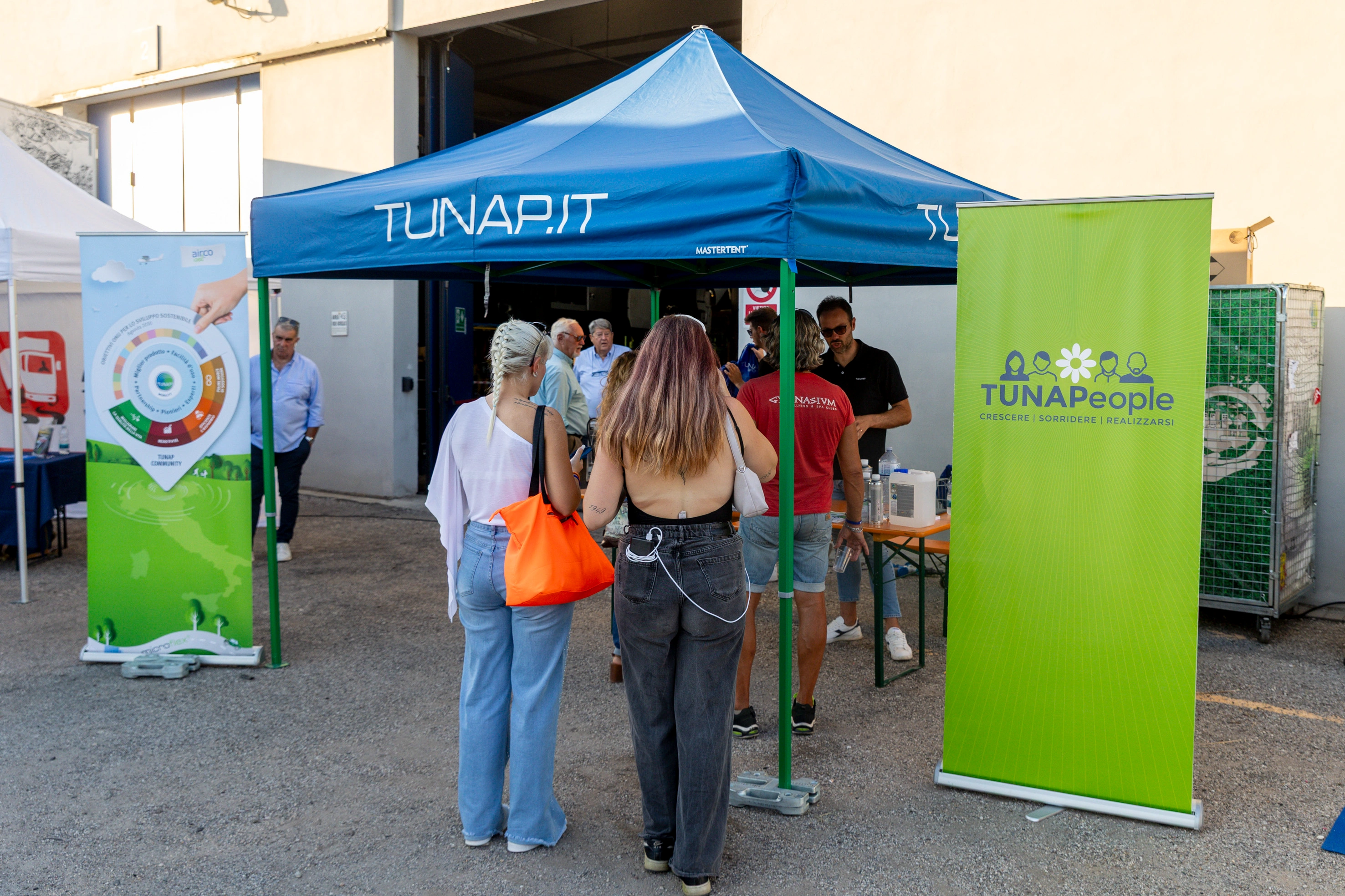 Persone che interagiscono con gli stand aziendali di TUNAPIT e TUNAPeople.