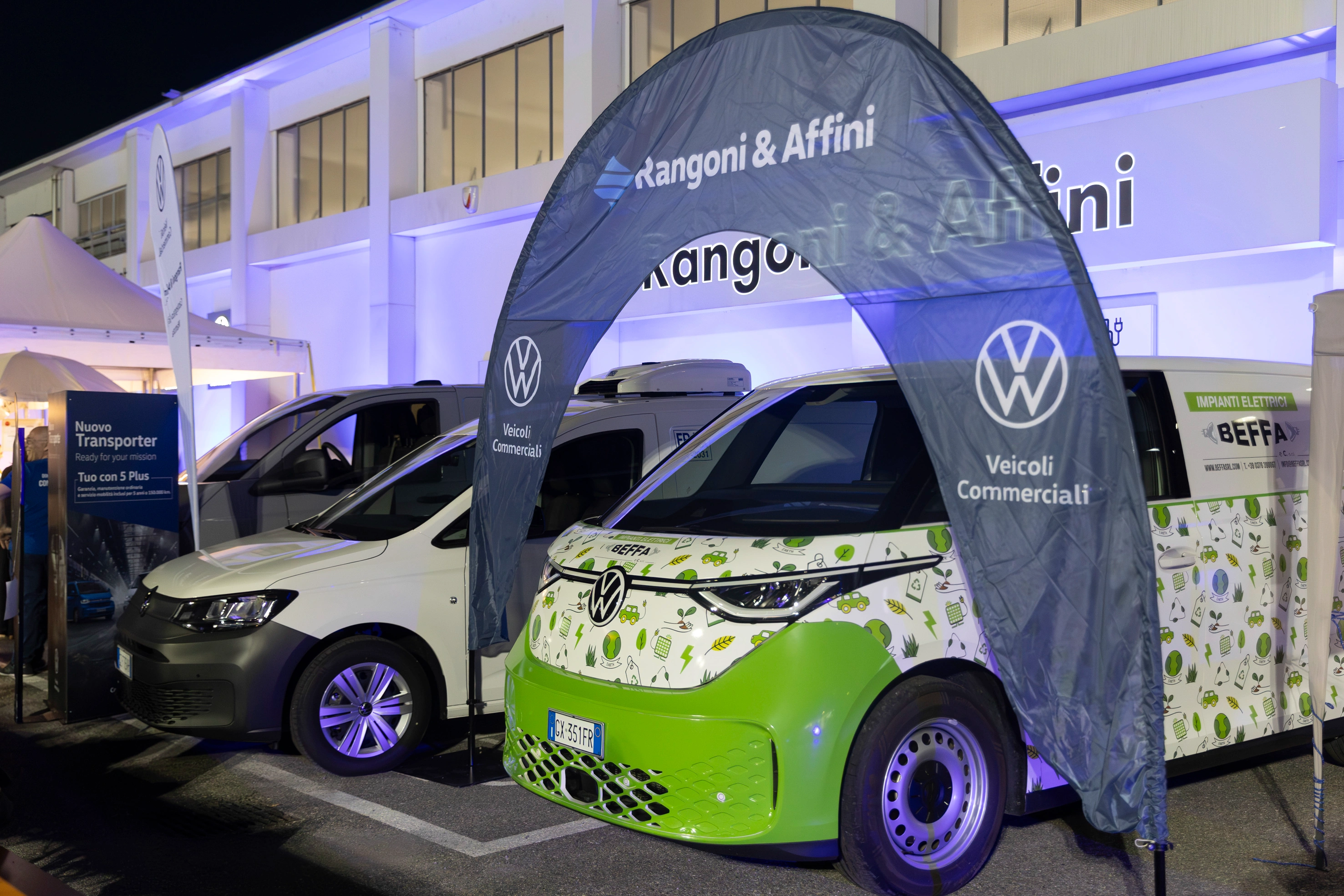 Esposizione di furgoni Volkswagen commerciali, inclusa un'ID. Buzz elettrica verde con tema "ecologico".