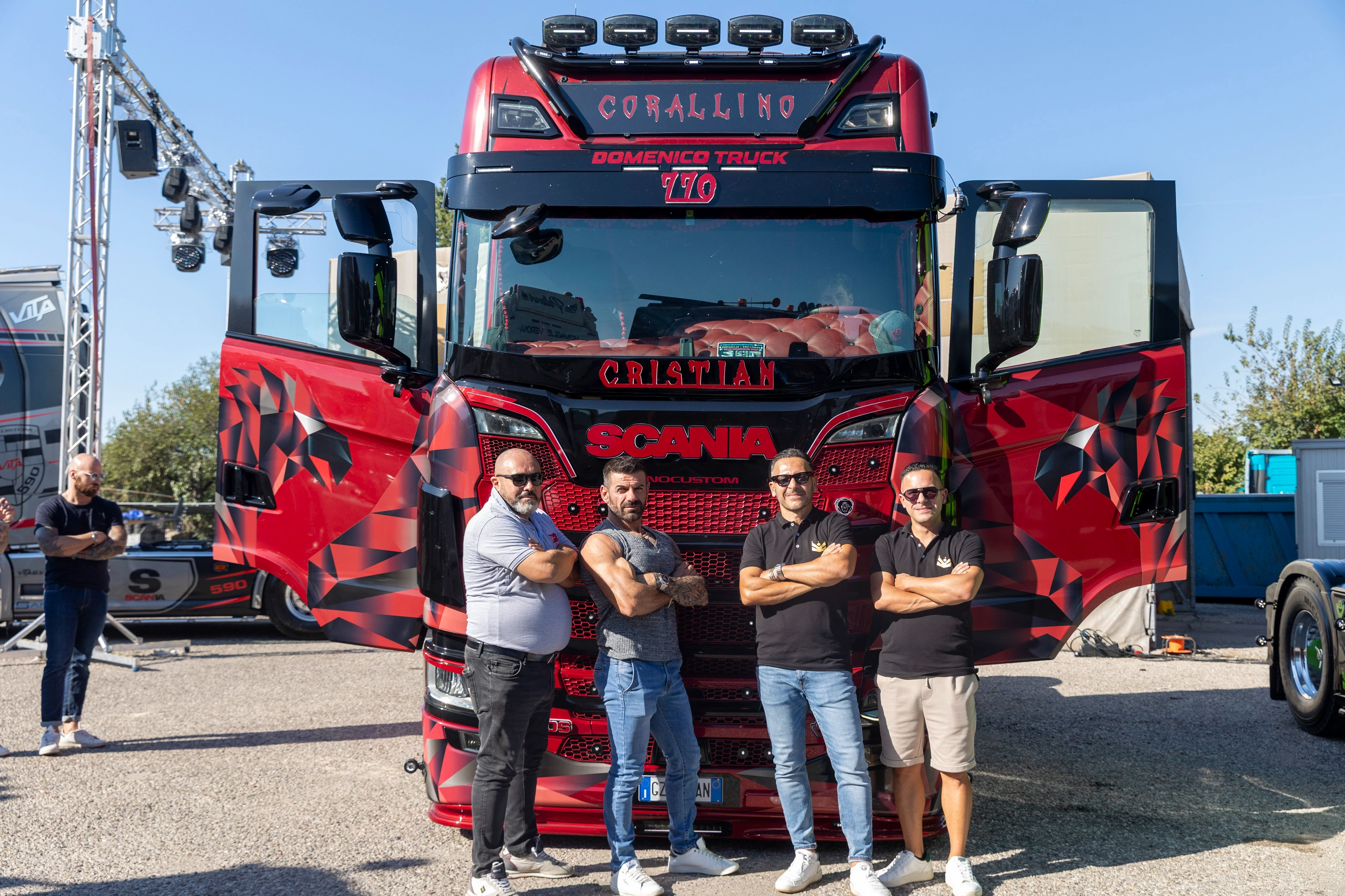 Quattro uomini si ergono davanti a un camion rosso Scania personalizzato con le porte aperte.
