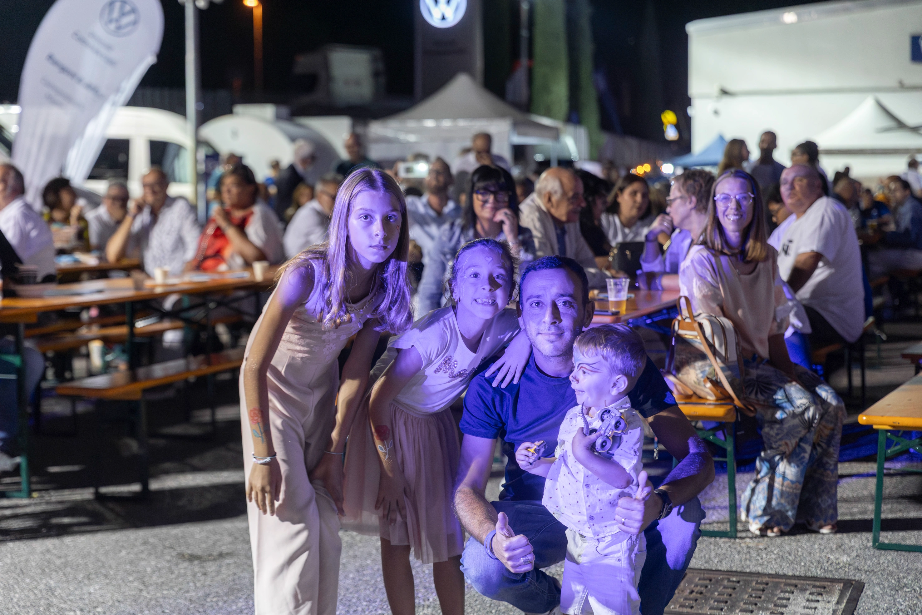 Una famiglia posa per una foto in un evento affollato.