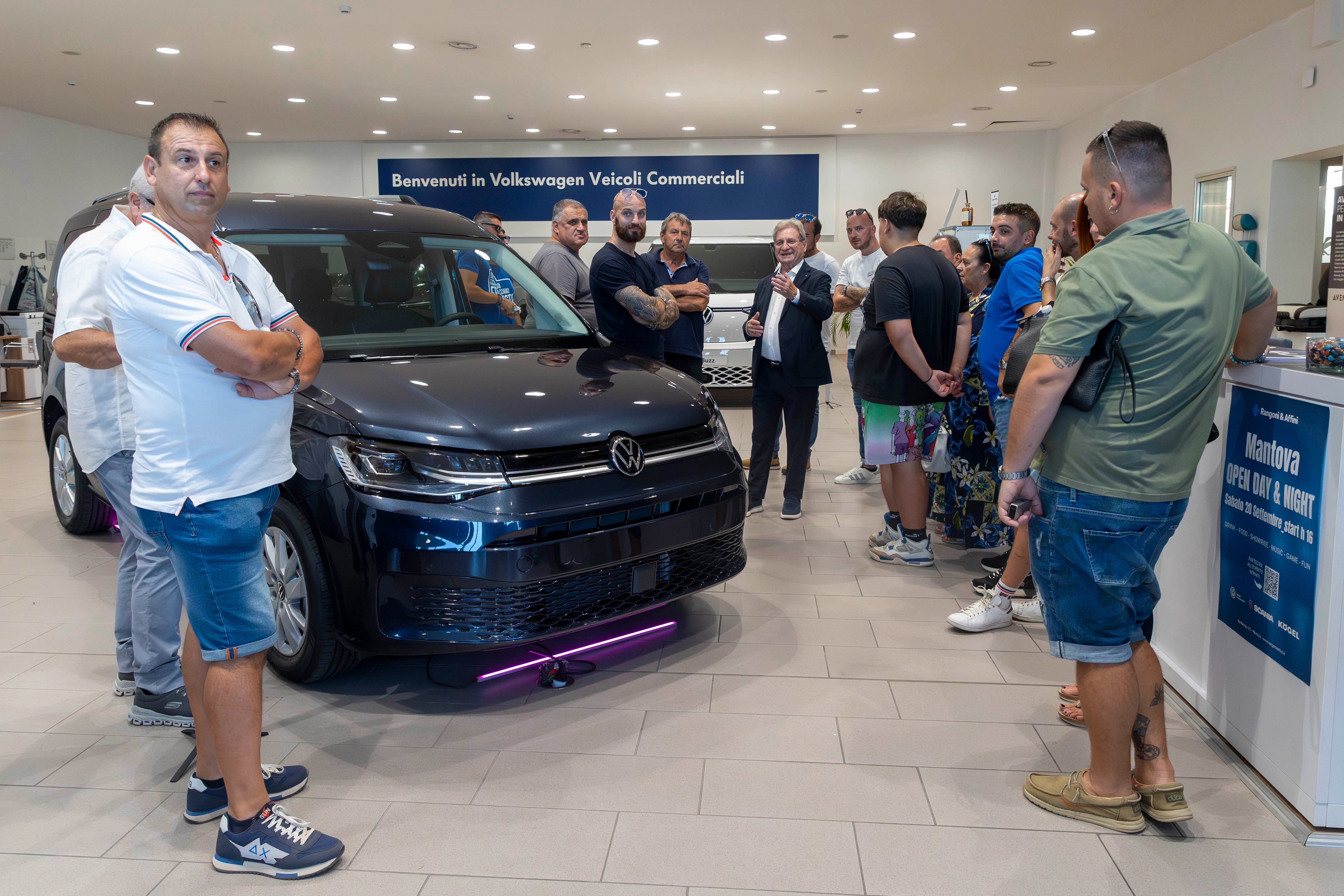 Persone riunite attorno a un'auto Volkswagen commerciale in una concessionaria.
