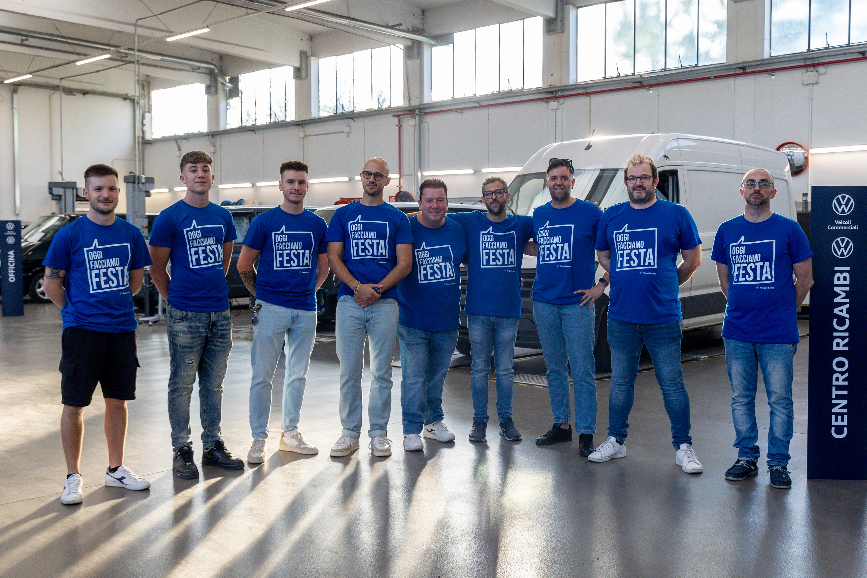 Un gruppo di persone indossa magliette blu con la scritta "OGGI FACCIAMO FESTA".